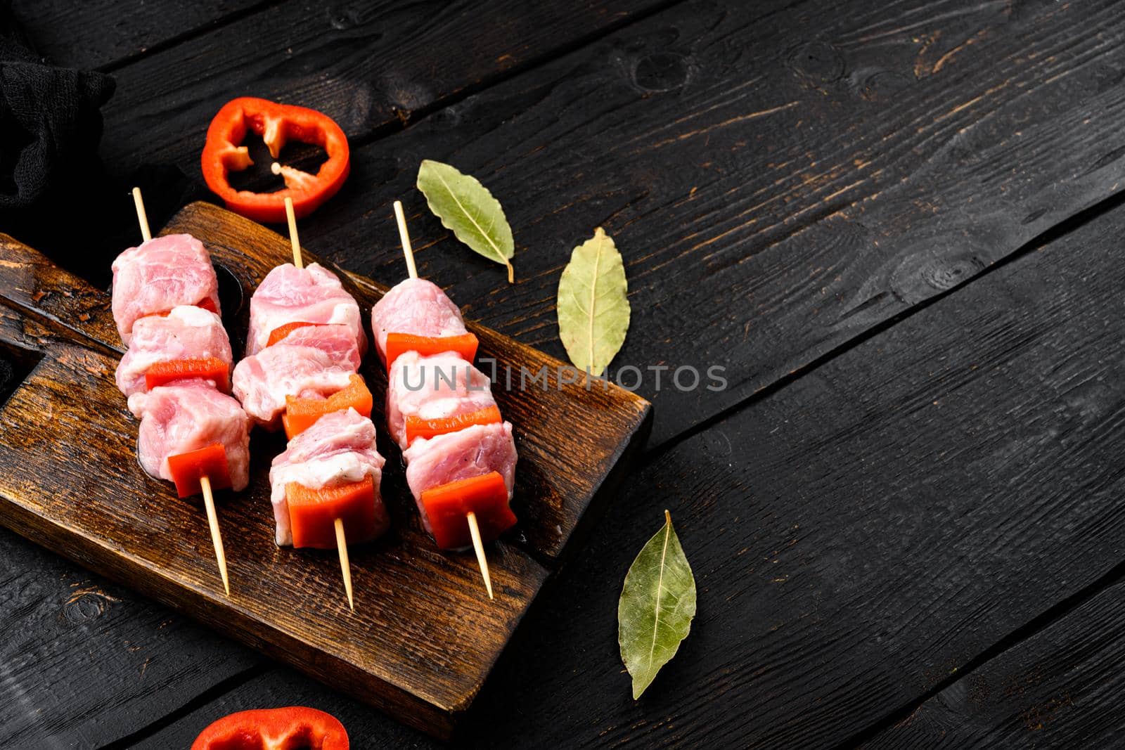 Uncooked Raw meat Chopsticks set, with copy space for text, on black wooden table background