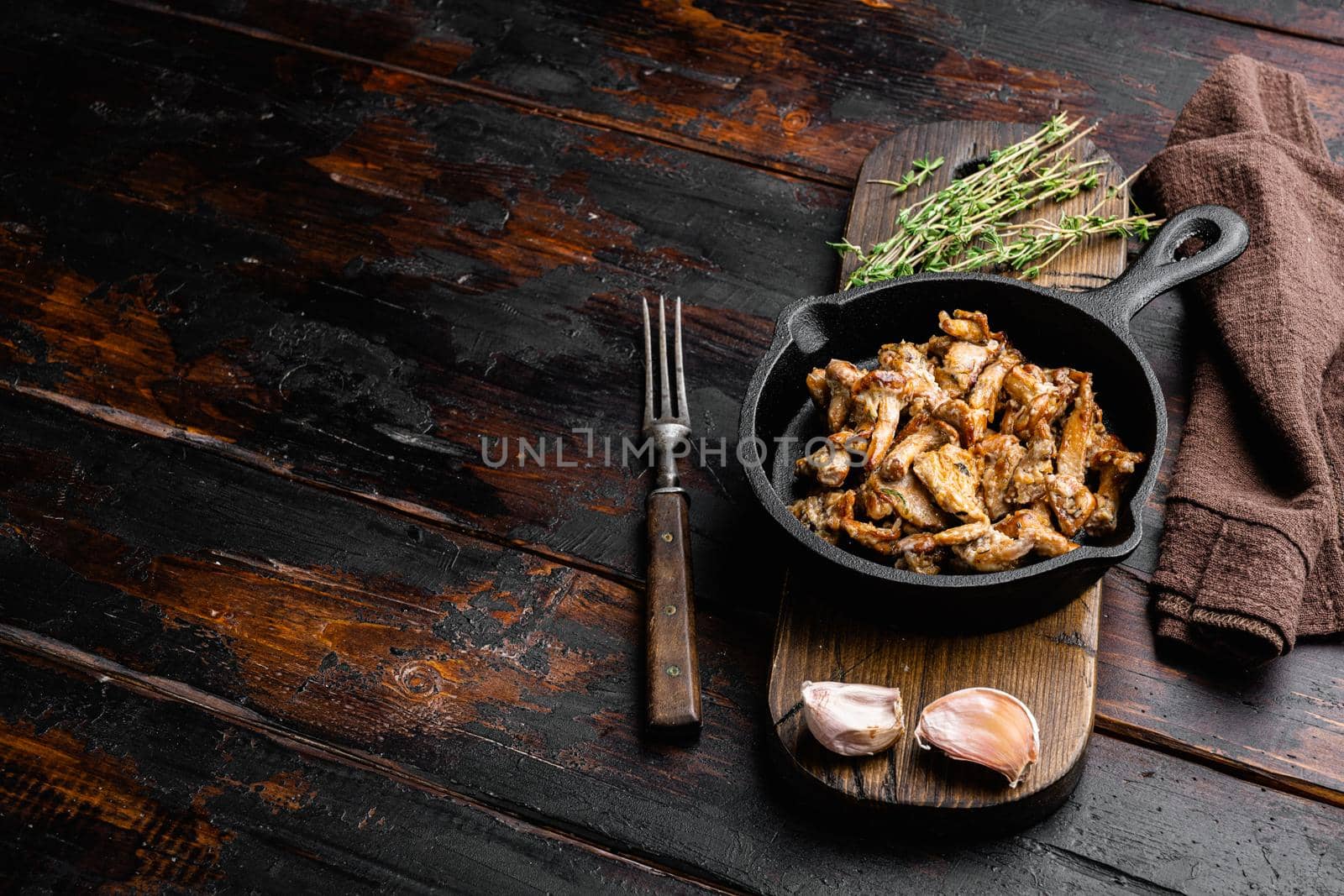 Autumn chantarelles prepared, in cast iron frying pan, on old dark wooden table background, with copy space for text by Ilianesolenyi