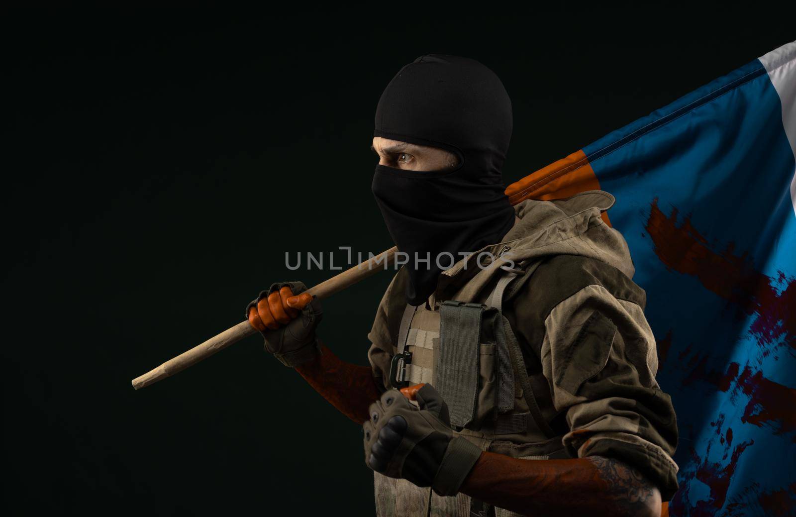 a male soldier in a military uniform with a balaclava and hands covered in blood holds a bloody flag of Russia on a black background by Rotozey