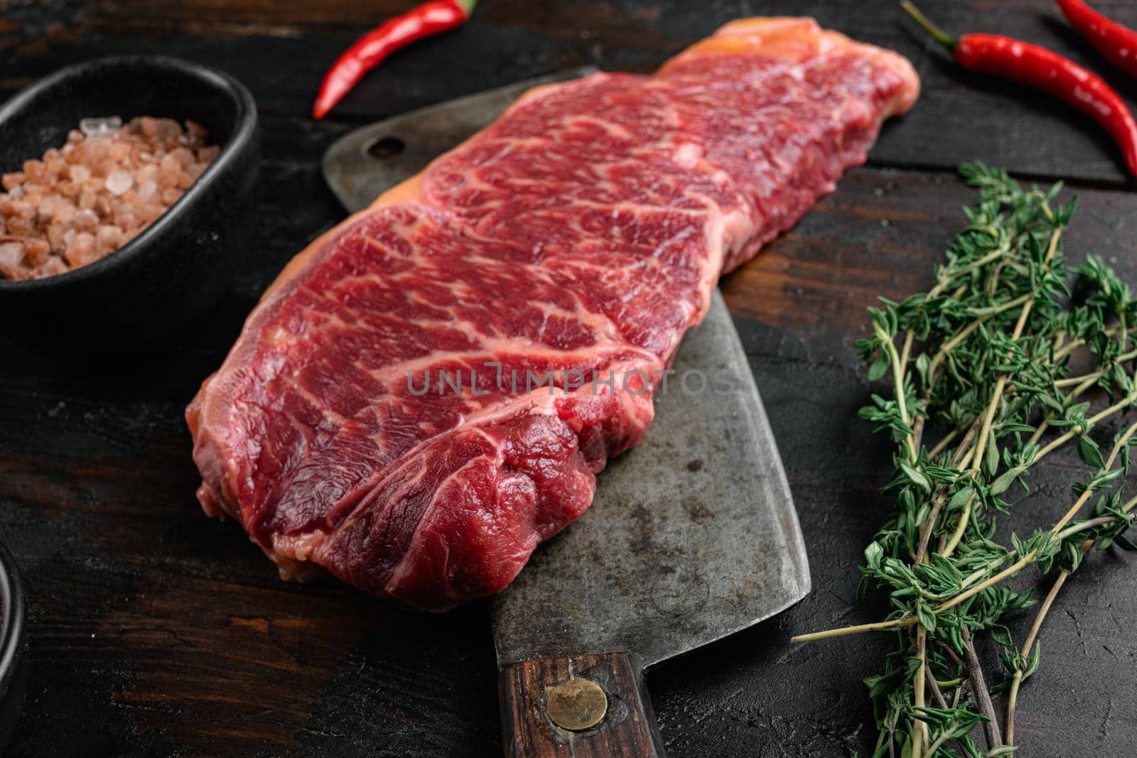 Raw Grass Fed NY Strip Steaks with Salt and Pepper, on old dark wooden table background by Ilianesolenyi