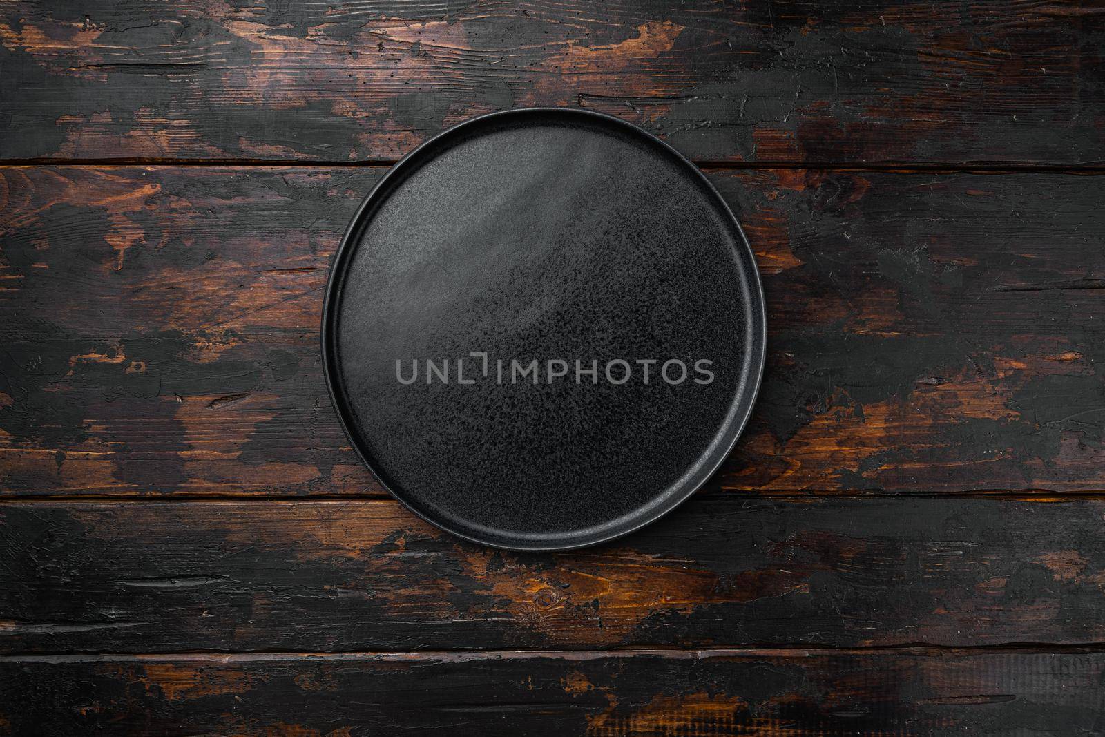 Black plate, on old dark wooden table background by Ilianesolenyi
