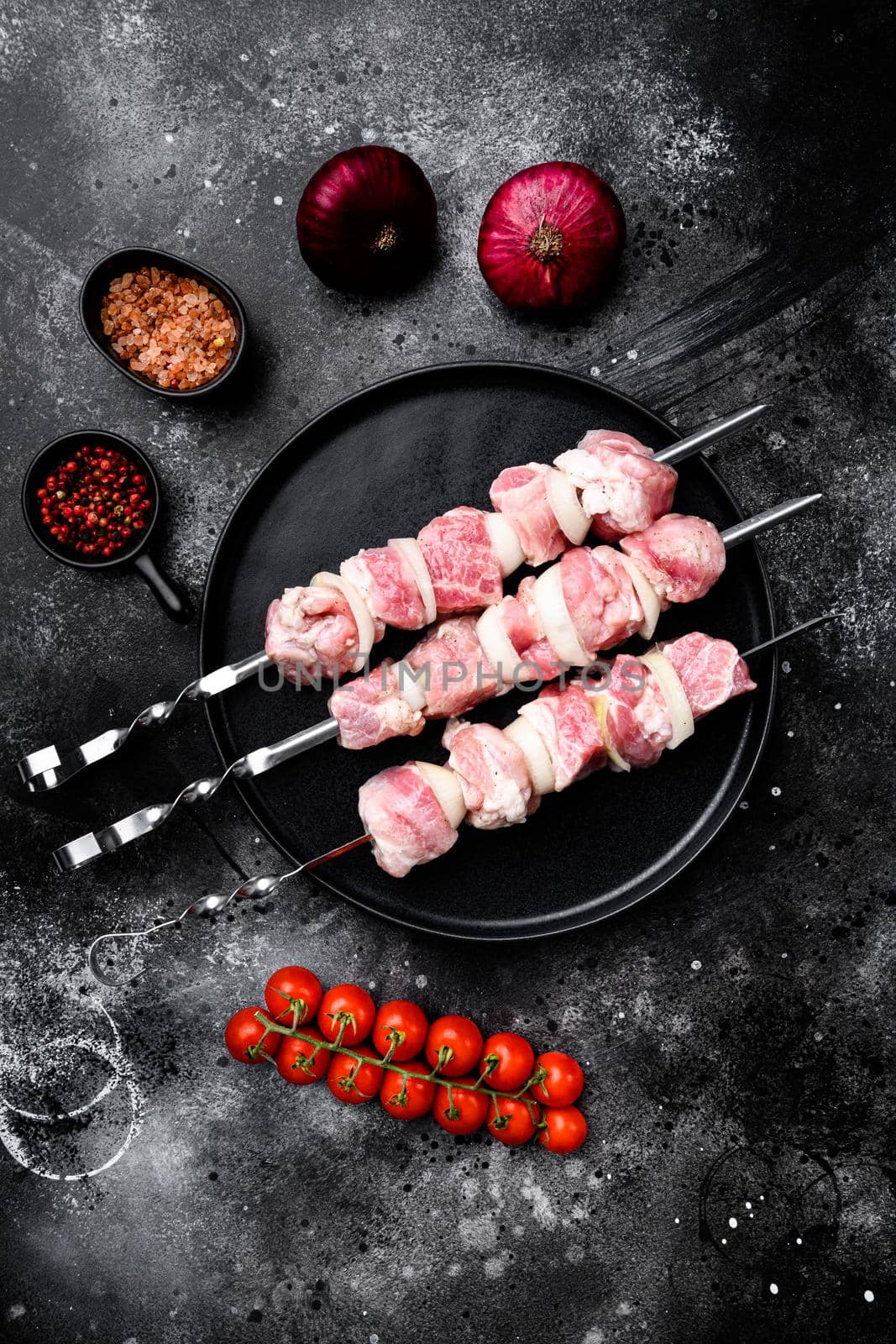 Raw pork shish kebab. BBQ meat with vegetables, top view flat lay, with copy space for text, on black dark stone table background by Ilianesolenyi
