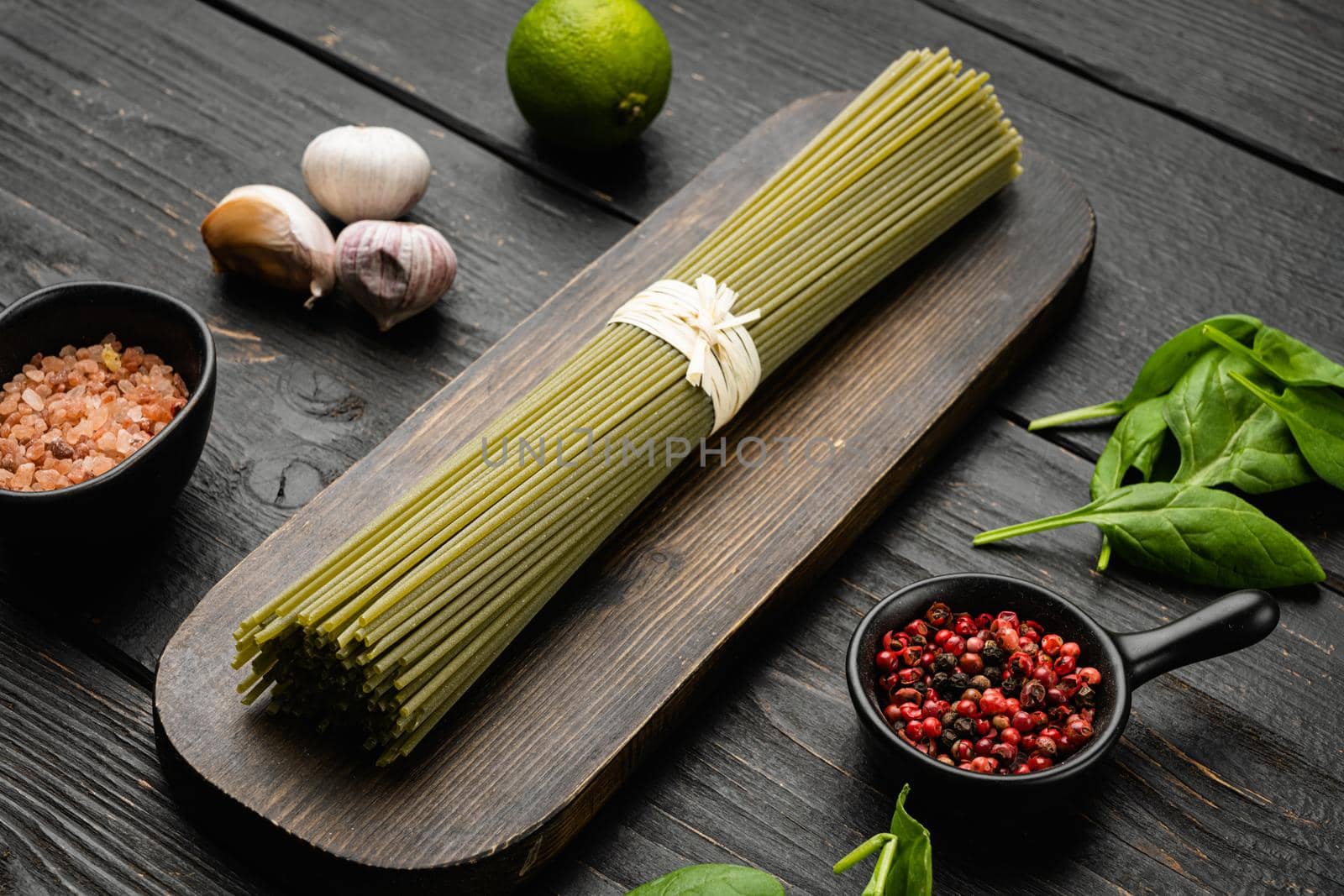 Italian uncooked green pasta spaghetti set, on black wooden table background