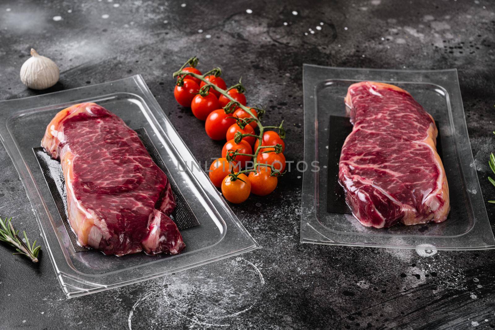 Unopened vacuum pack of meat set, on black dark stone table background