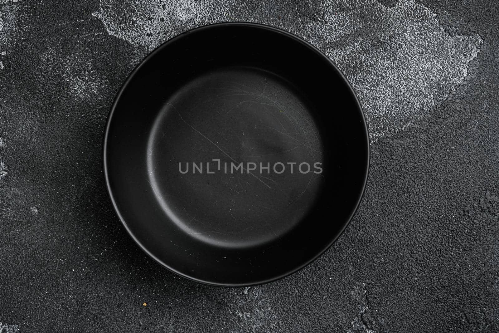 black pottery bowl, with copy space for text or food, with copy space for text or food, top view flat lay , on black dark stone table background by Ilianesolenyi