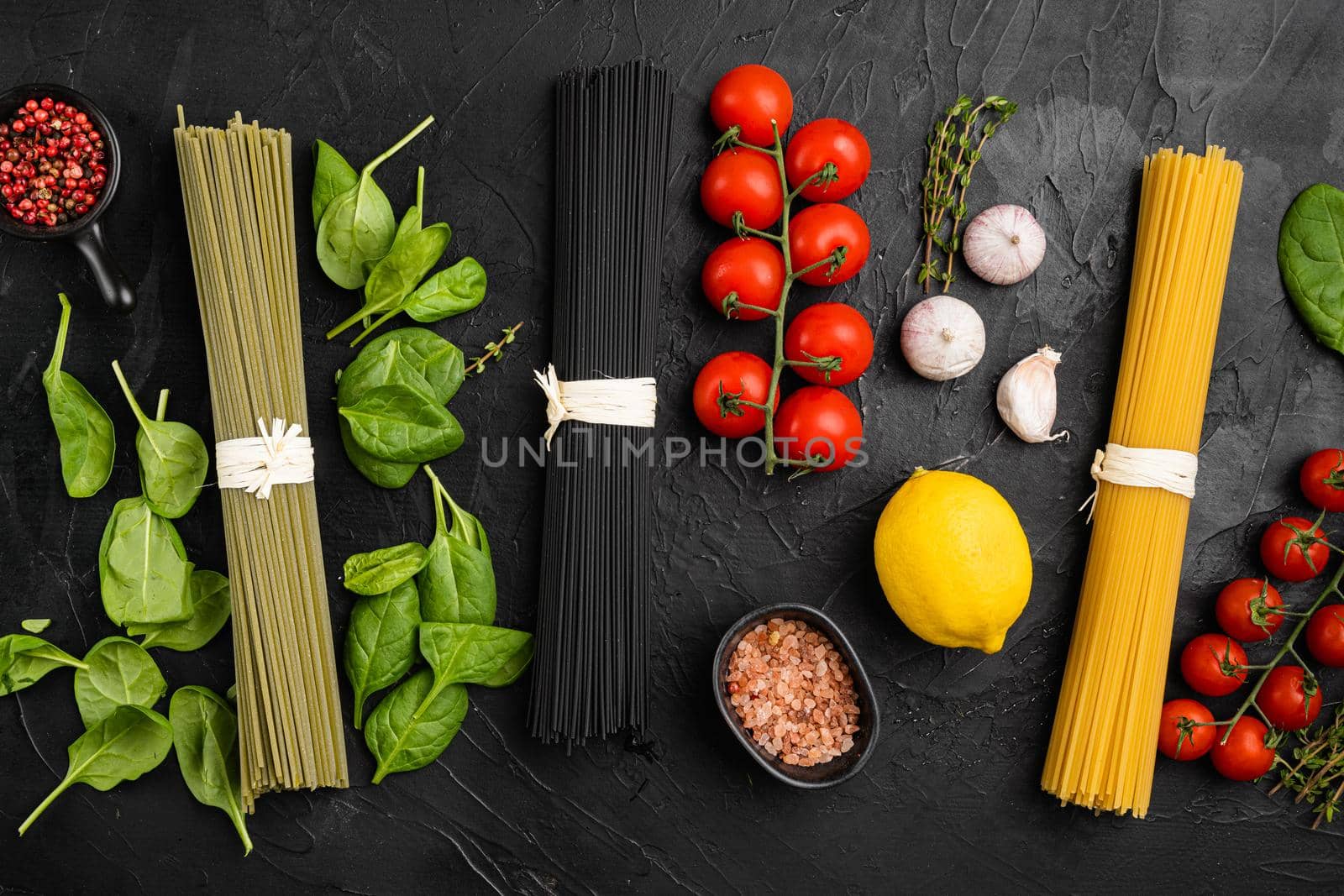 Colored spaghetti raw dry, on black dark stone table background, top view flat lay by Ilianesolenyi