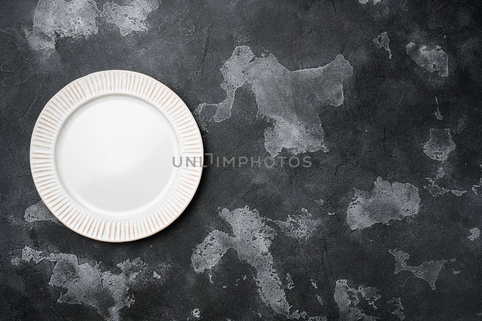 Empty white plate porcelain set with copy space for text or food with copy space for text or food, top view flat lay, on black dark stone table background