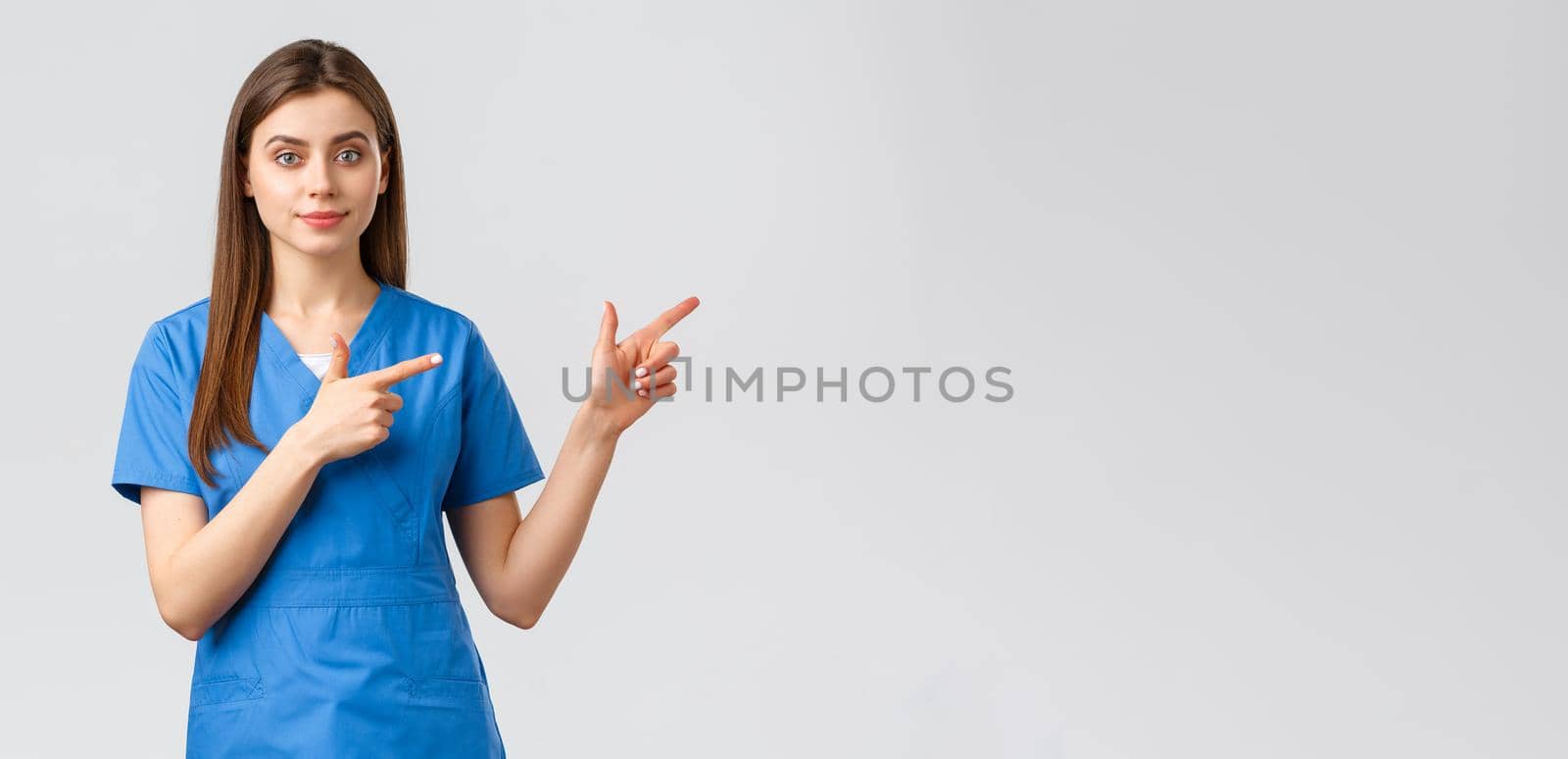 Healthcare workers, prevent virus, insurance and medicine concept. Young nurse or doctor in blue scrubs pointing fingers right, recommend banner or promo for clinic patients.