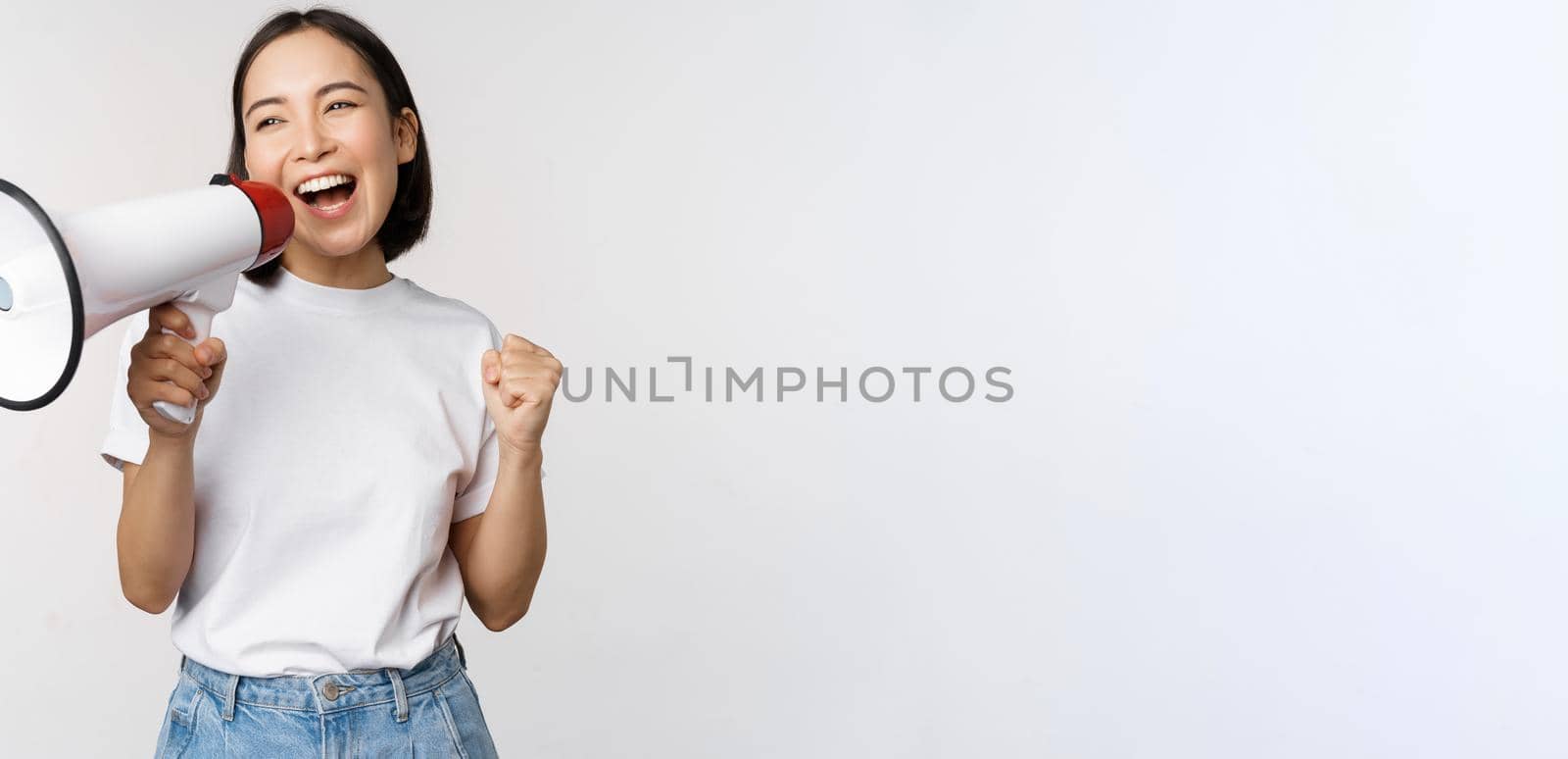 Asian girl shouting at megaphone, young activist protesting, using loud speakerphone, making announcement, white background by Benzoix