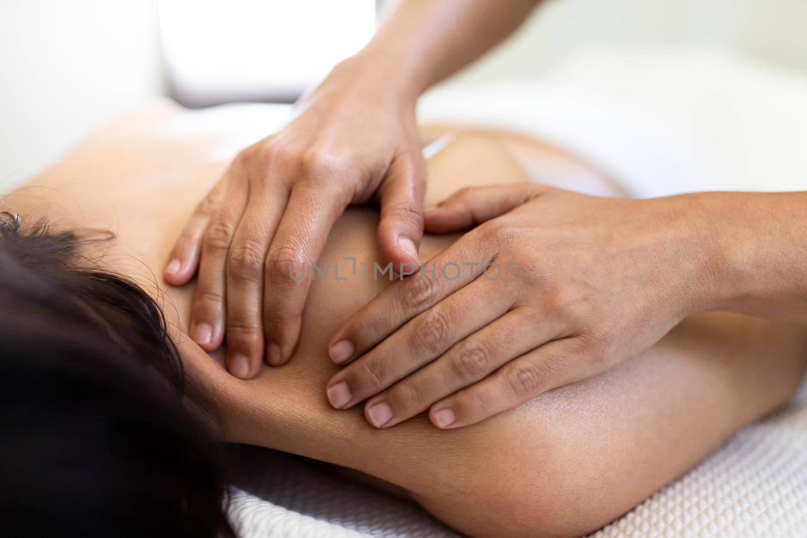 Closeup of woman hands giving a relaxing back massage to female client. Spa treatment concept. Bodycare concept.