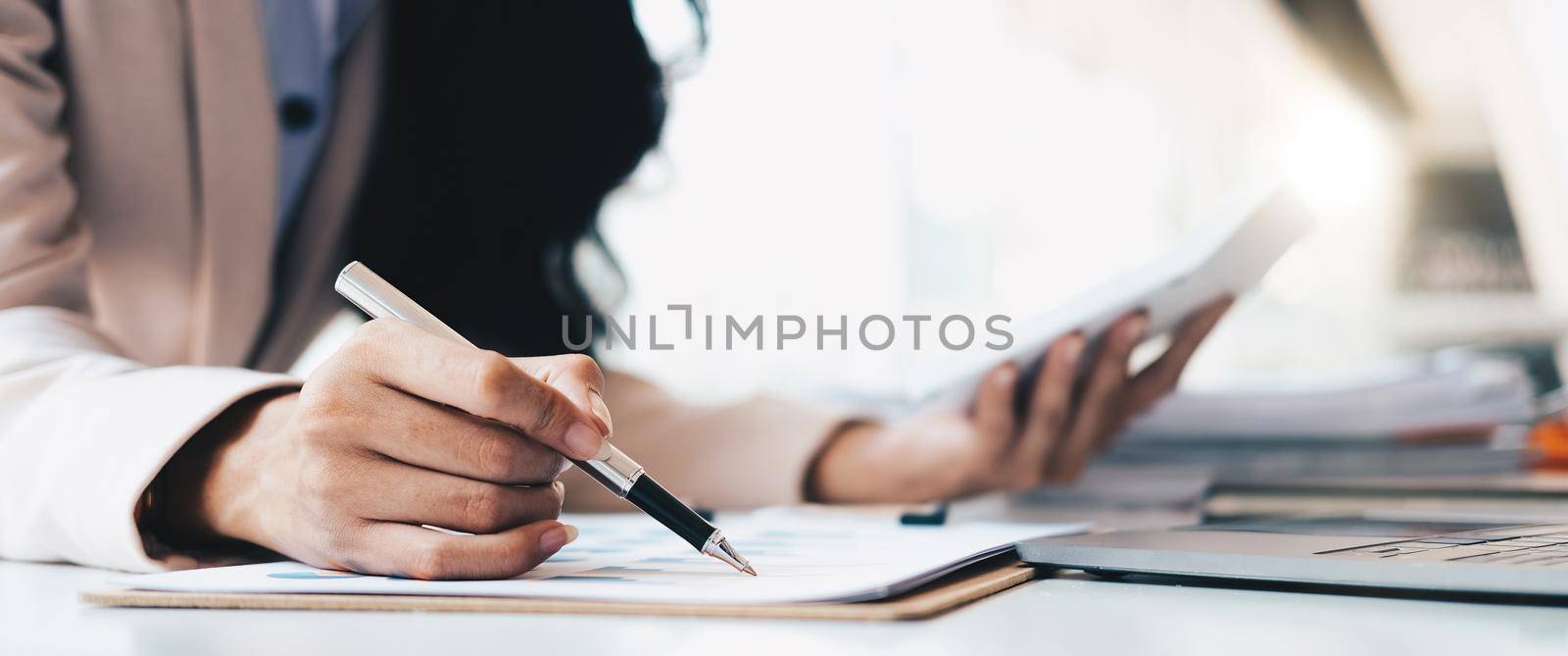 businesswoman or accountant pen pointing on graph chart while using calculator to calculate income tax and corporate income in office by nateemee