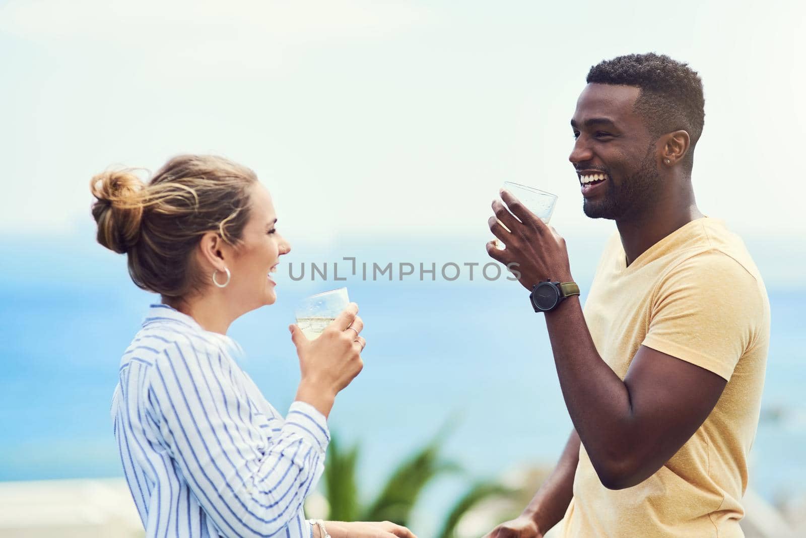 We deserved this holiday after the year weve had. Shot of a young couple enjoying drinks together while relaxing outdoors on holiday. by YuriArcurs