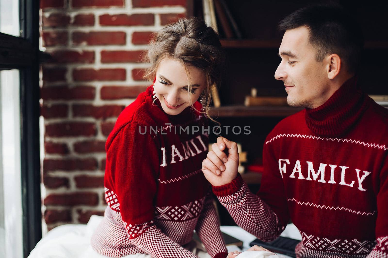 Sensuality couple in red sweaters having fun together, celebrating new year. by StudioLucky