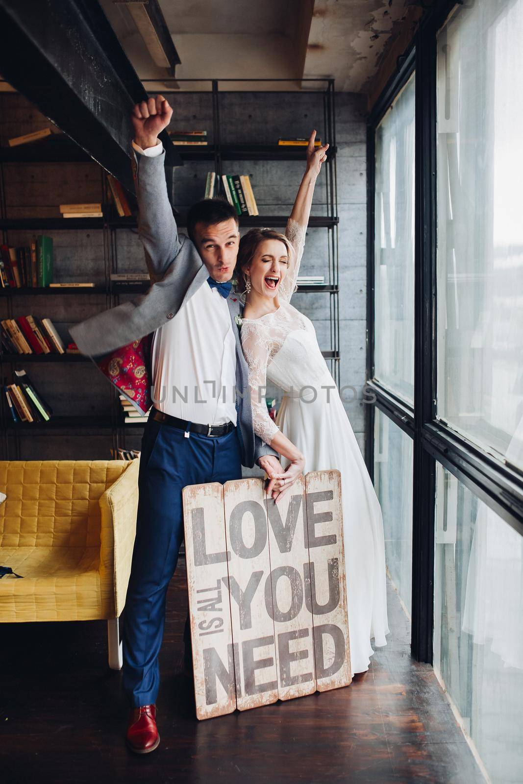 Loving couple kissing holding signboard all you need is love. by StudioLucky
