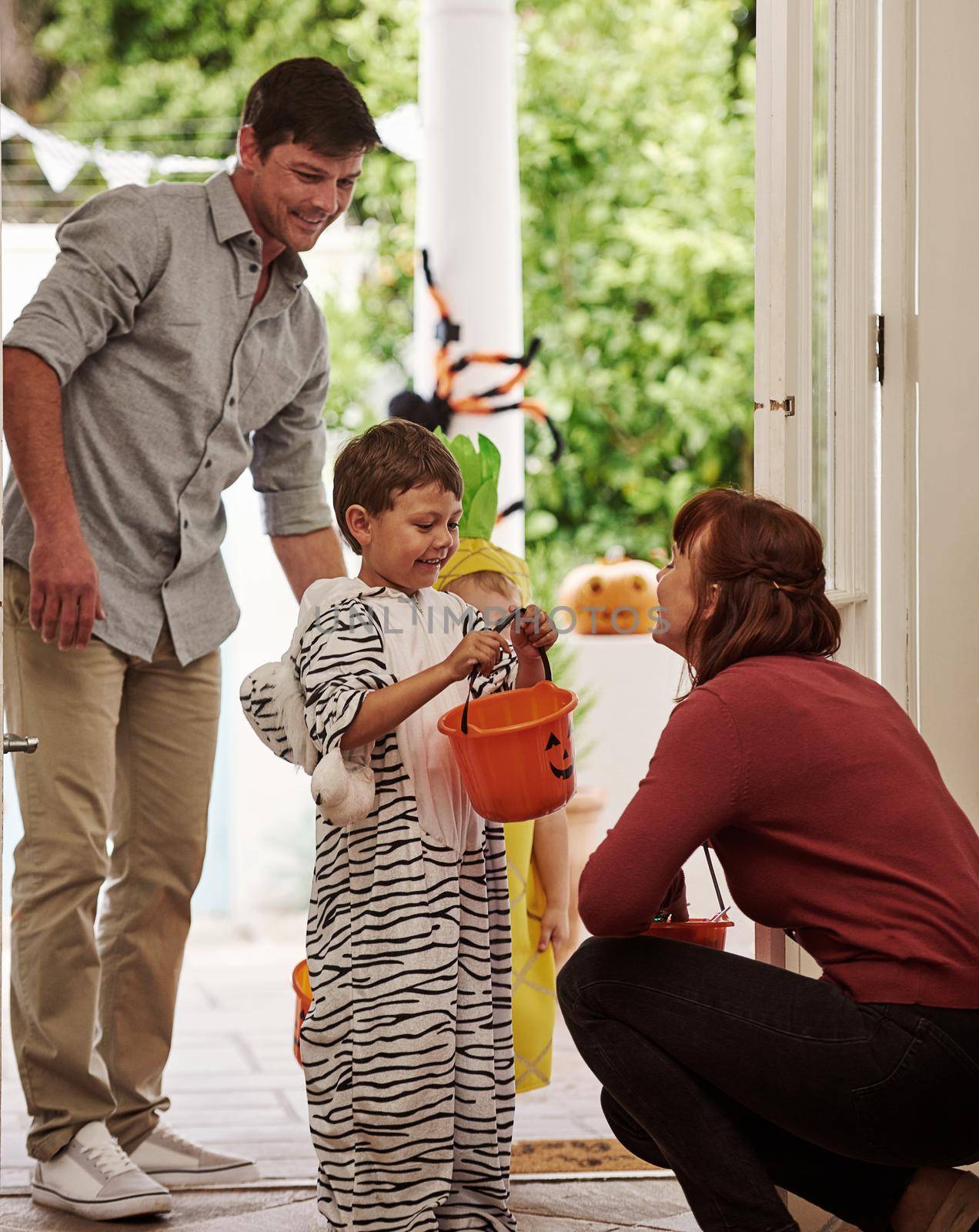 Trick or treat. Shot of two adorable little boys celebrating halloween with their parents at home. by YuriArcurs