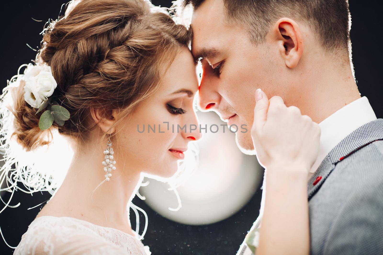 Gorgeous bride and handsome groom touching by faces each other. by StudioLucky