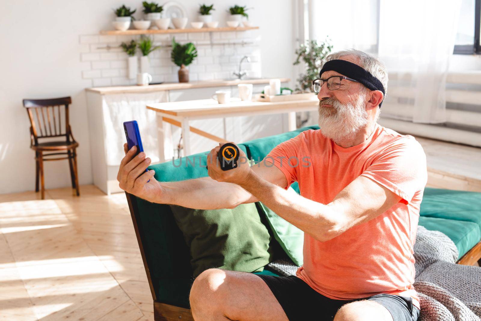 Senior man taking selfie for social network during doing fitness exercise at home with dumbbells - elderly people and wellness health and internet concept by Satura86