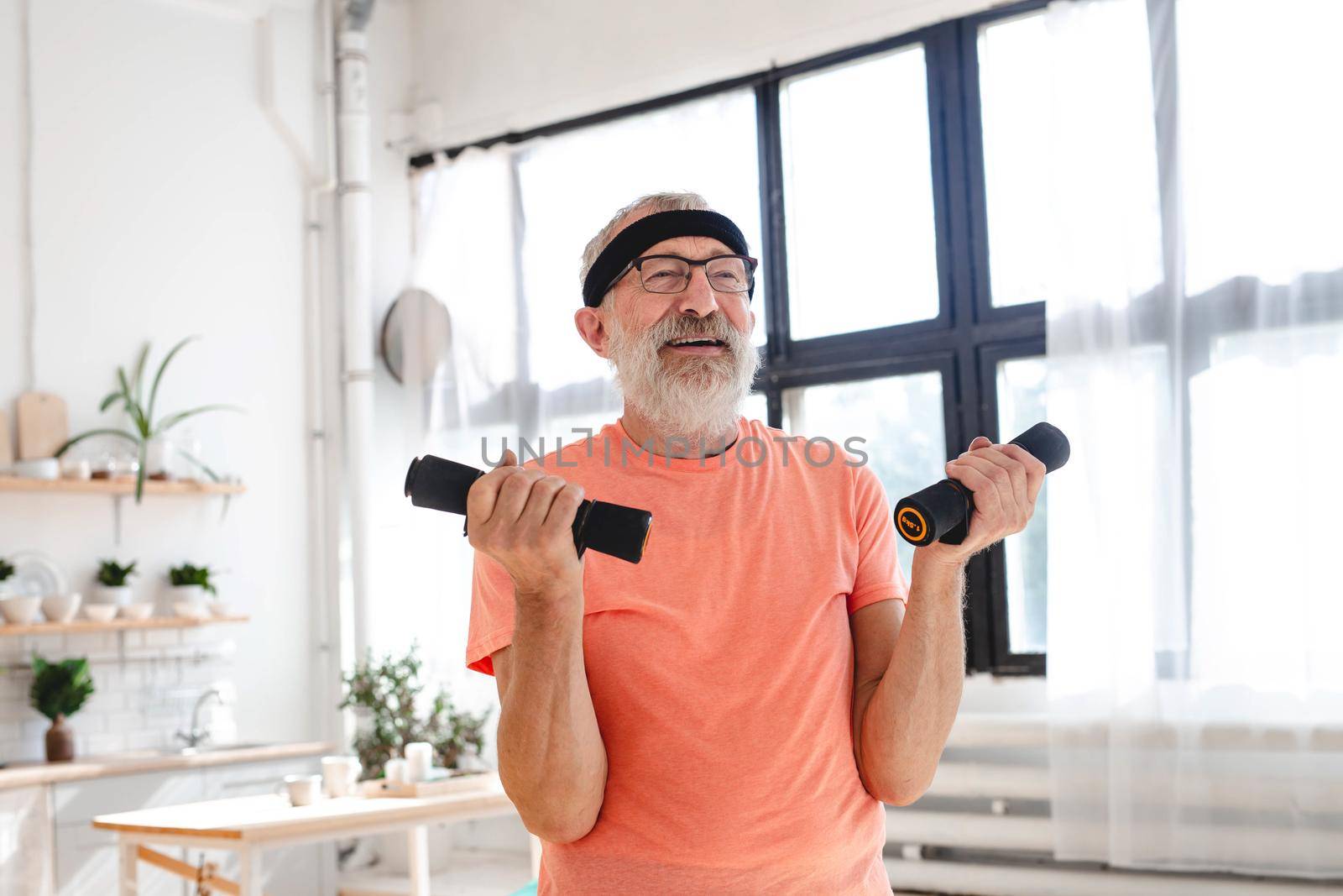 Senior man doing fitness exercise at home with dumbbells - elderly people and wellness health