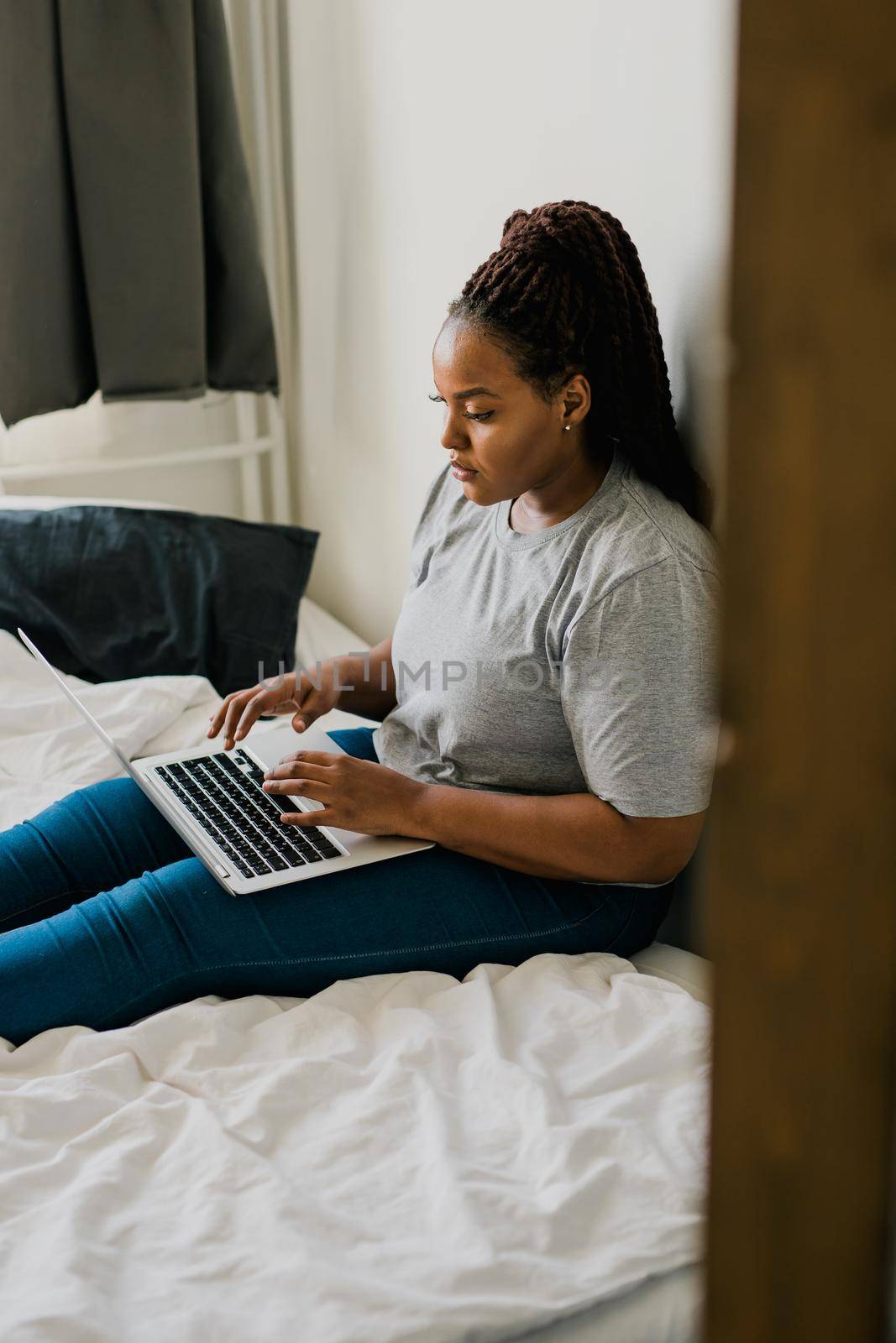 African american young woman using laptop on bed - technologies and communication and social network concept by Satura86