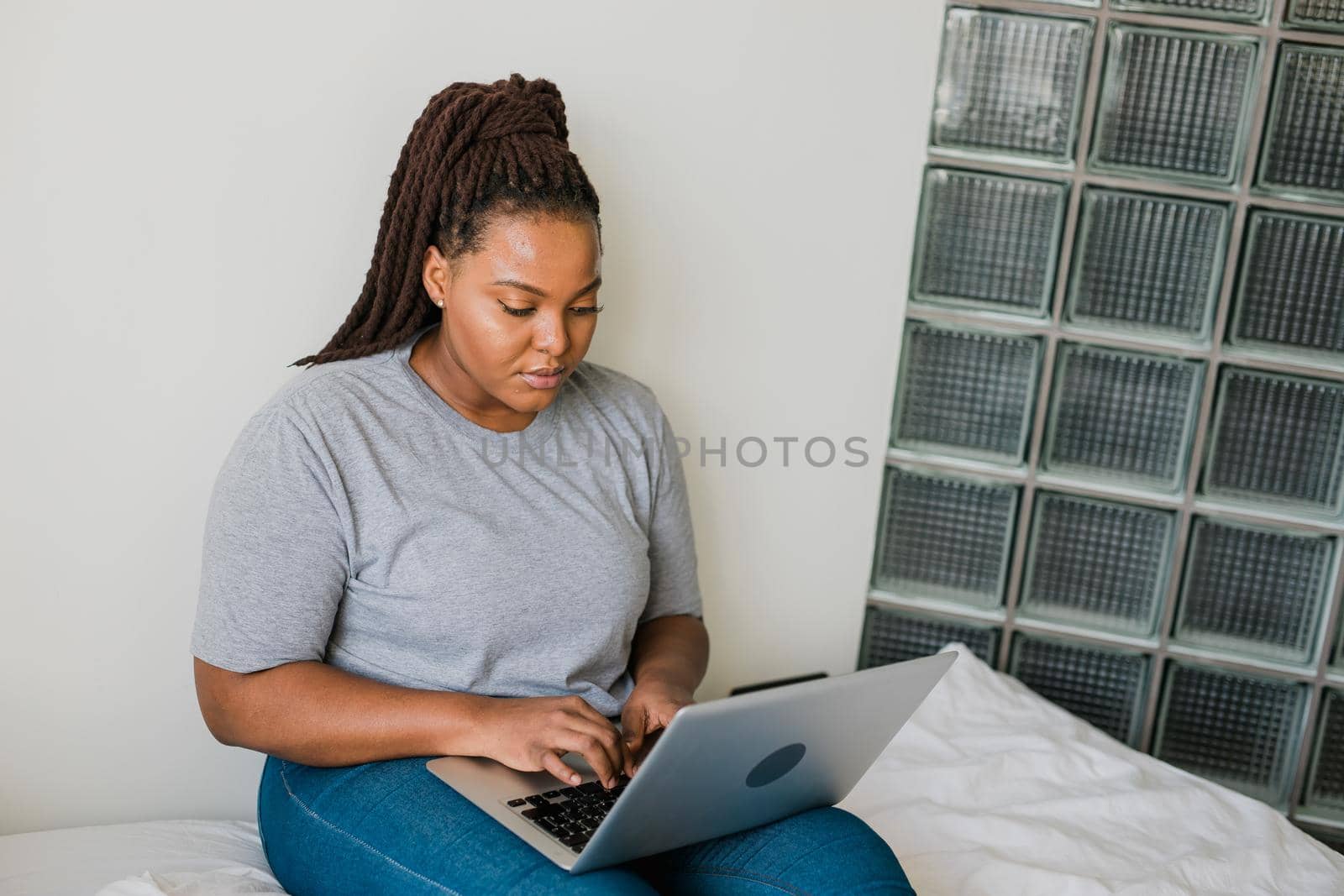 African american young woman using laptop on bed - technologies and communication and social network concept by Satura86