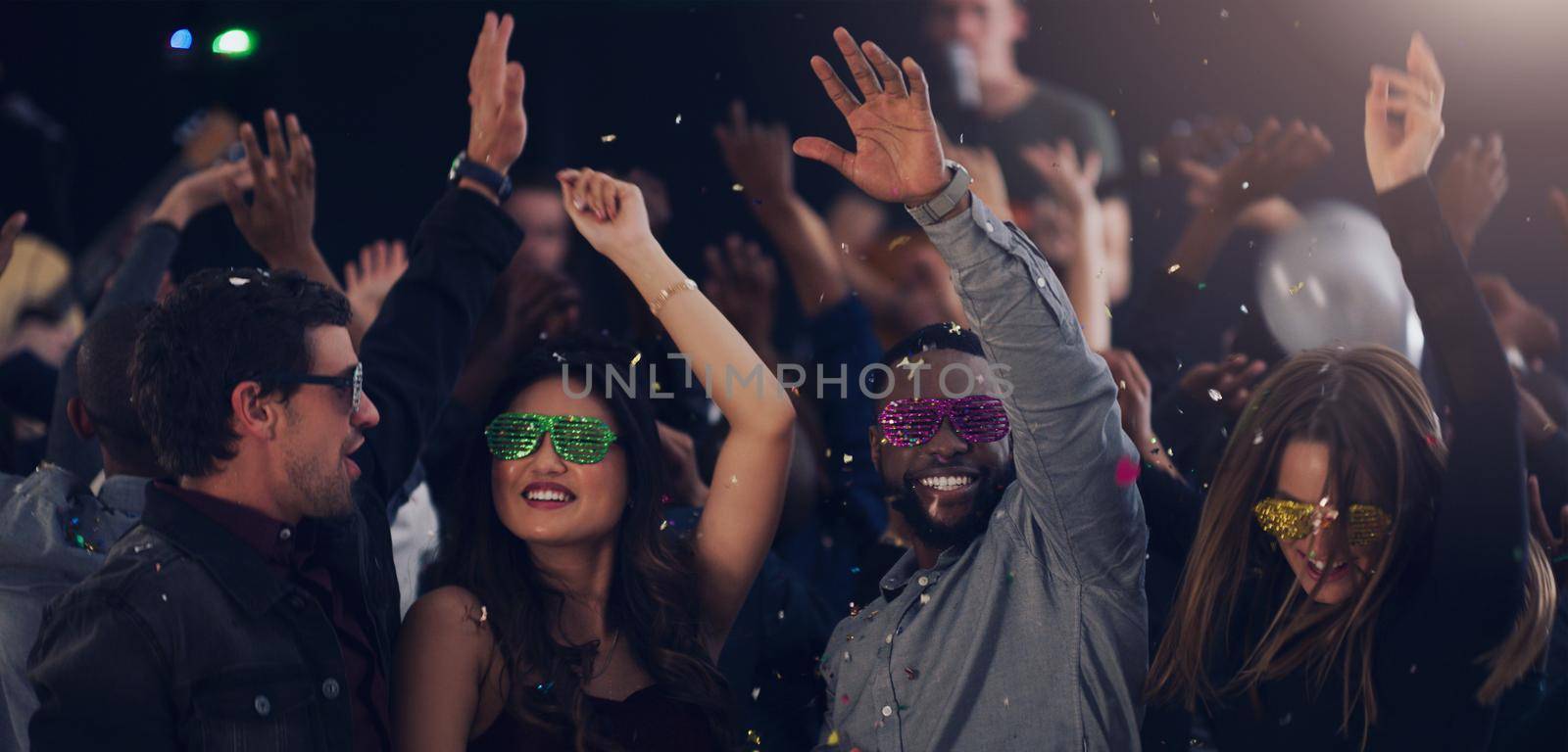 Another year spent together. Cropped shot of a group of young friends dancing together in a nightclub. by YuriArcurs