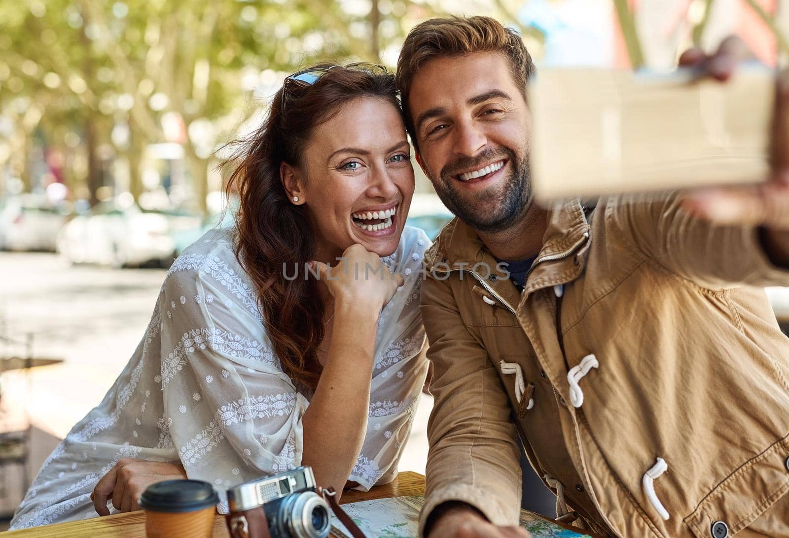Shot of a happy tourist couple taking a selfie while relaxing at a sidewalk cafe together.