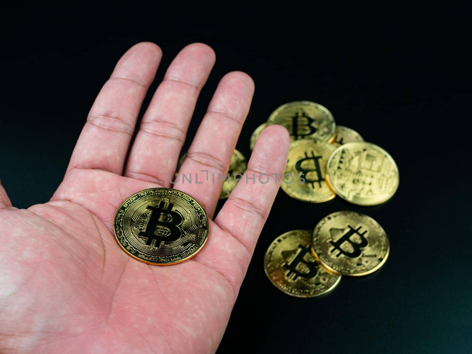 bitcoin coin placed on the hand on a black background by Unimages2527