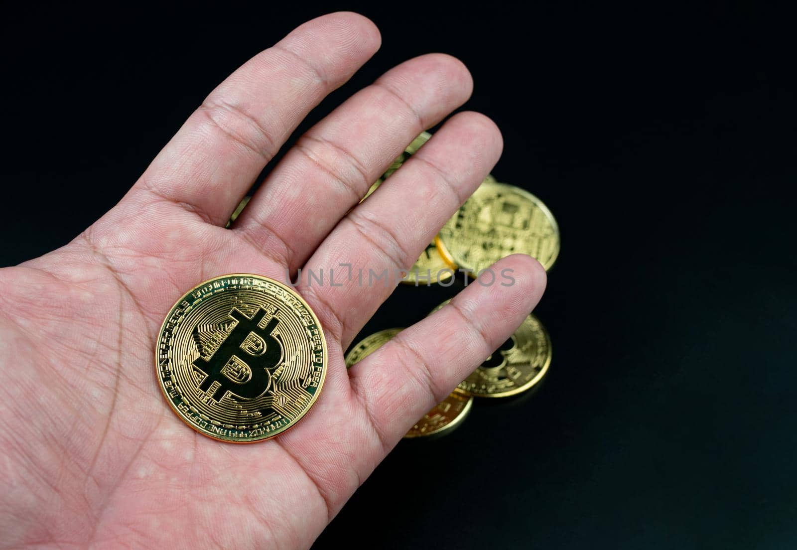 bitcoin coin placed on the hand on a black background by Unimages2527