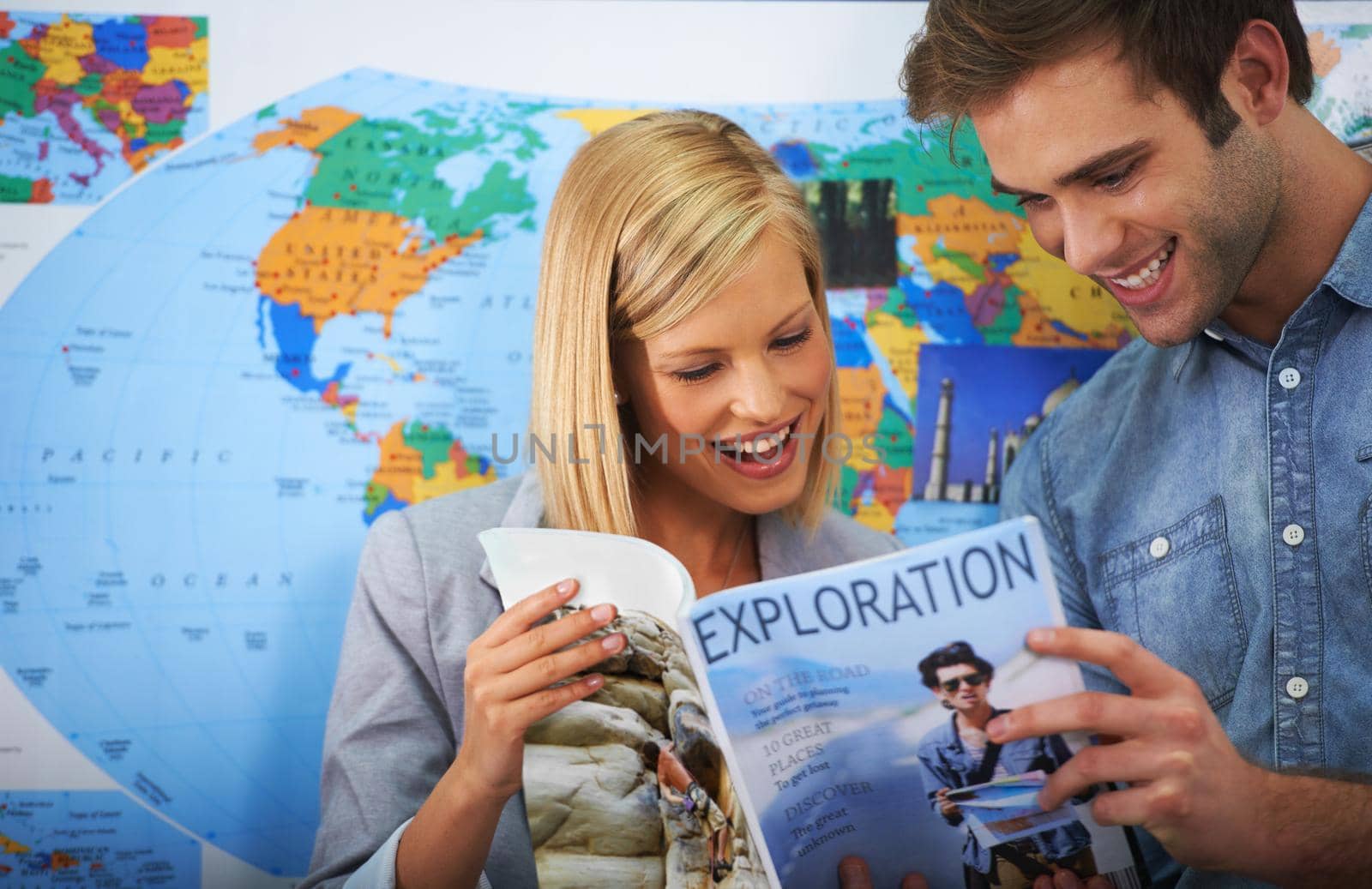 This place has our names written all over it. Shot of a young couple looking at a travel brochure. by YuriArcurs