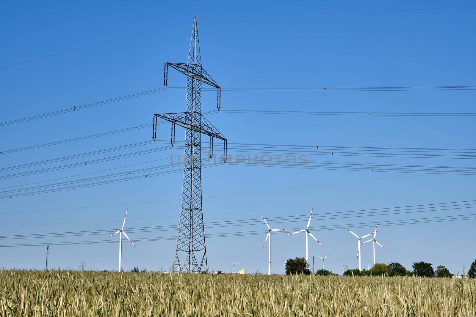 Electricity pylon with power lines and wind turbines in the background seen in Germany