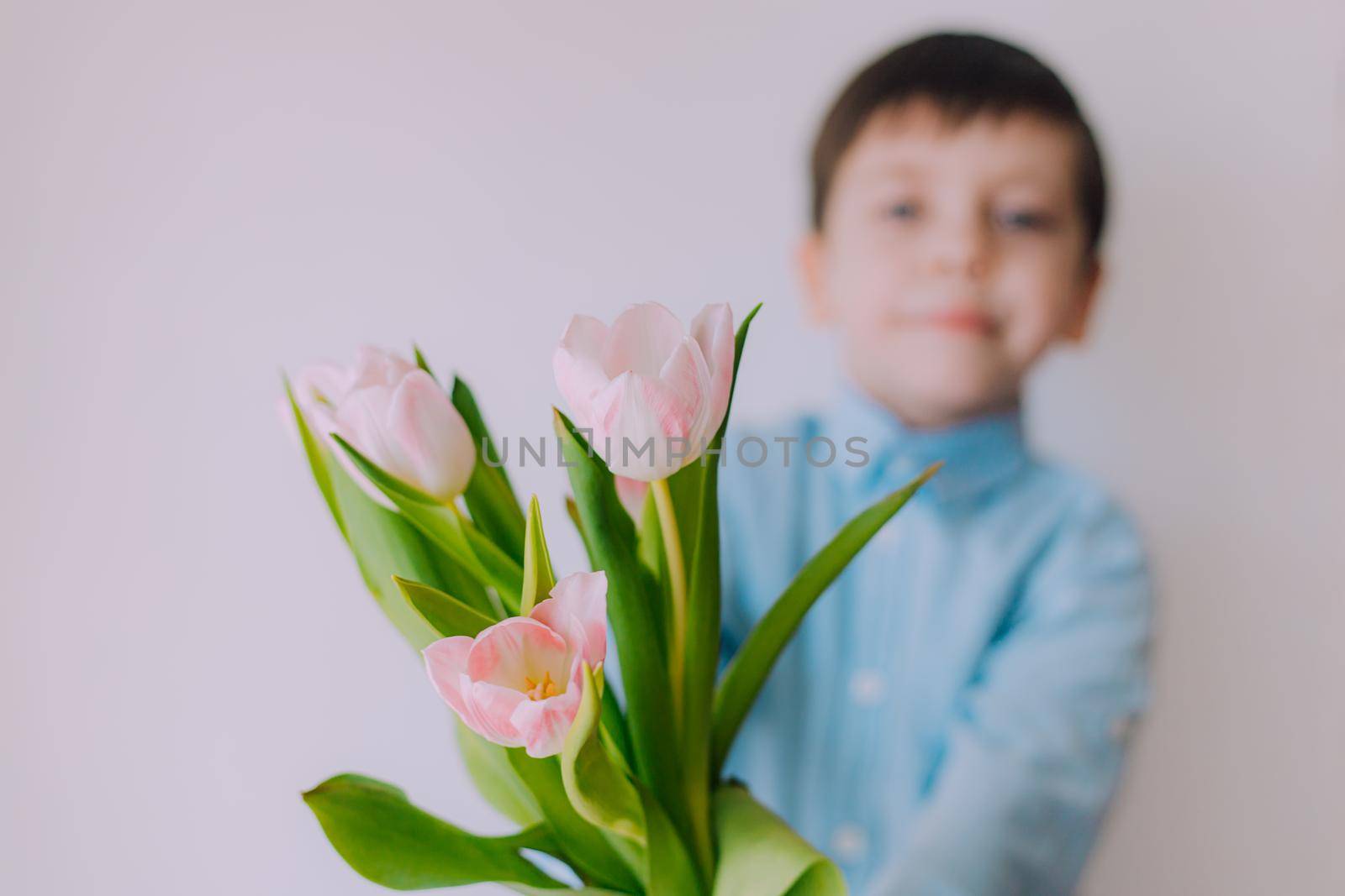 A boy with a bouquet of tulips lifestyle . Postcard for March 8. Congratulations on Women's Day. Congratulations on Mother's Day. Flowers are tulips. Baby and flowers