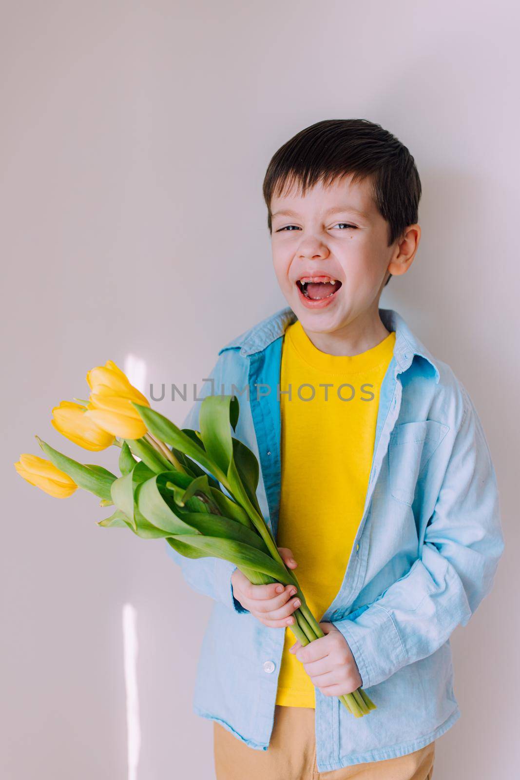 A boy with a bouquet of tulips lifestyle . Postcard for March 8. Congratulations on Women's Day. Congratulations on Mother's Day. Flowers are tulips. Baby and flowers