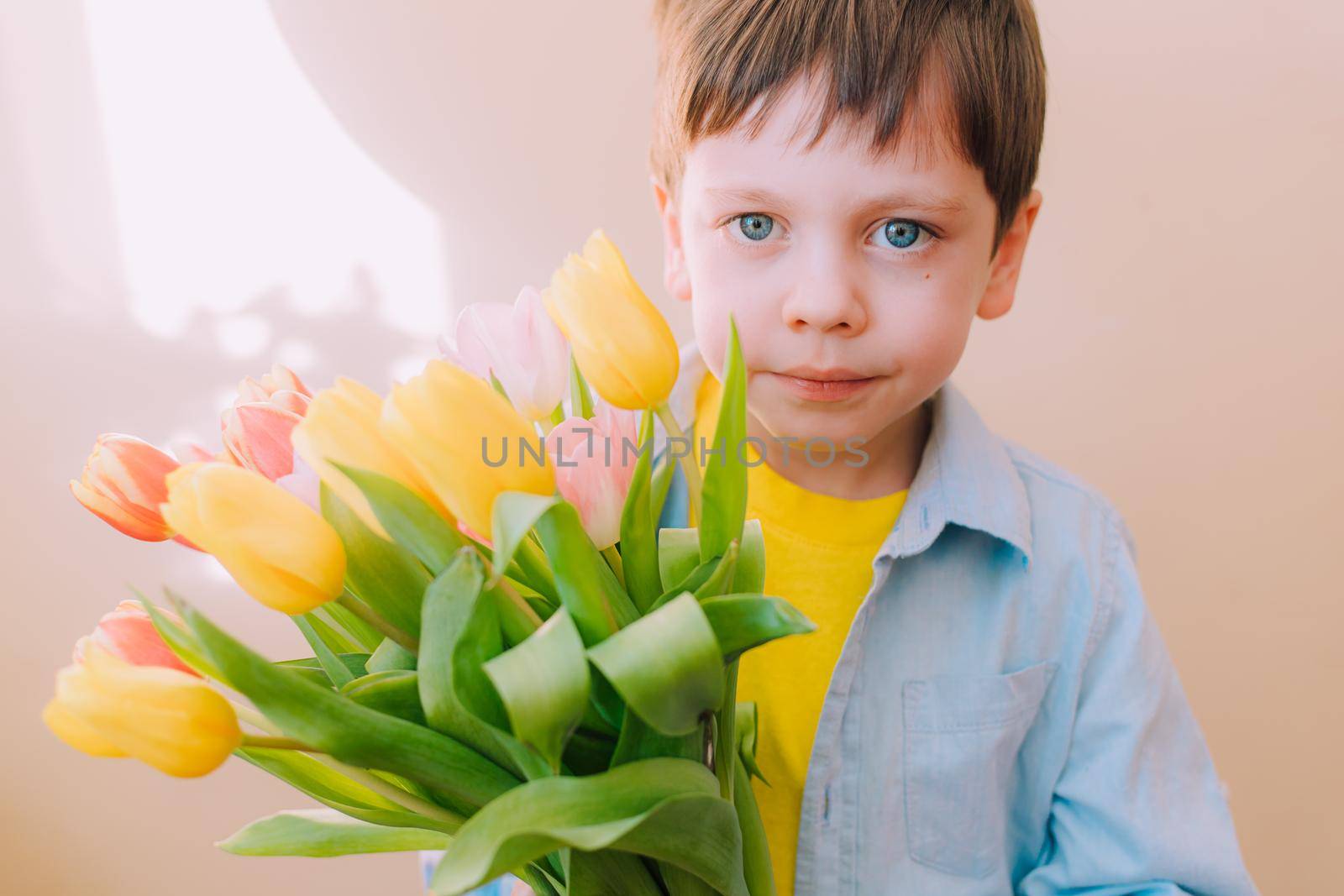 A boy with a bouquet of tulips lifestyle . Postcard for March 8. Congratulations on Women's Day. Congratulations on Mother's Day. Flowers are tulips. Baby and flowers