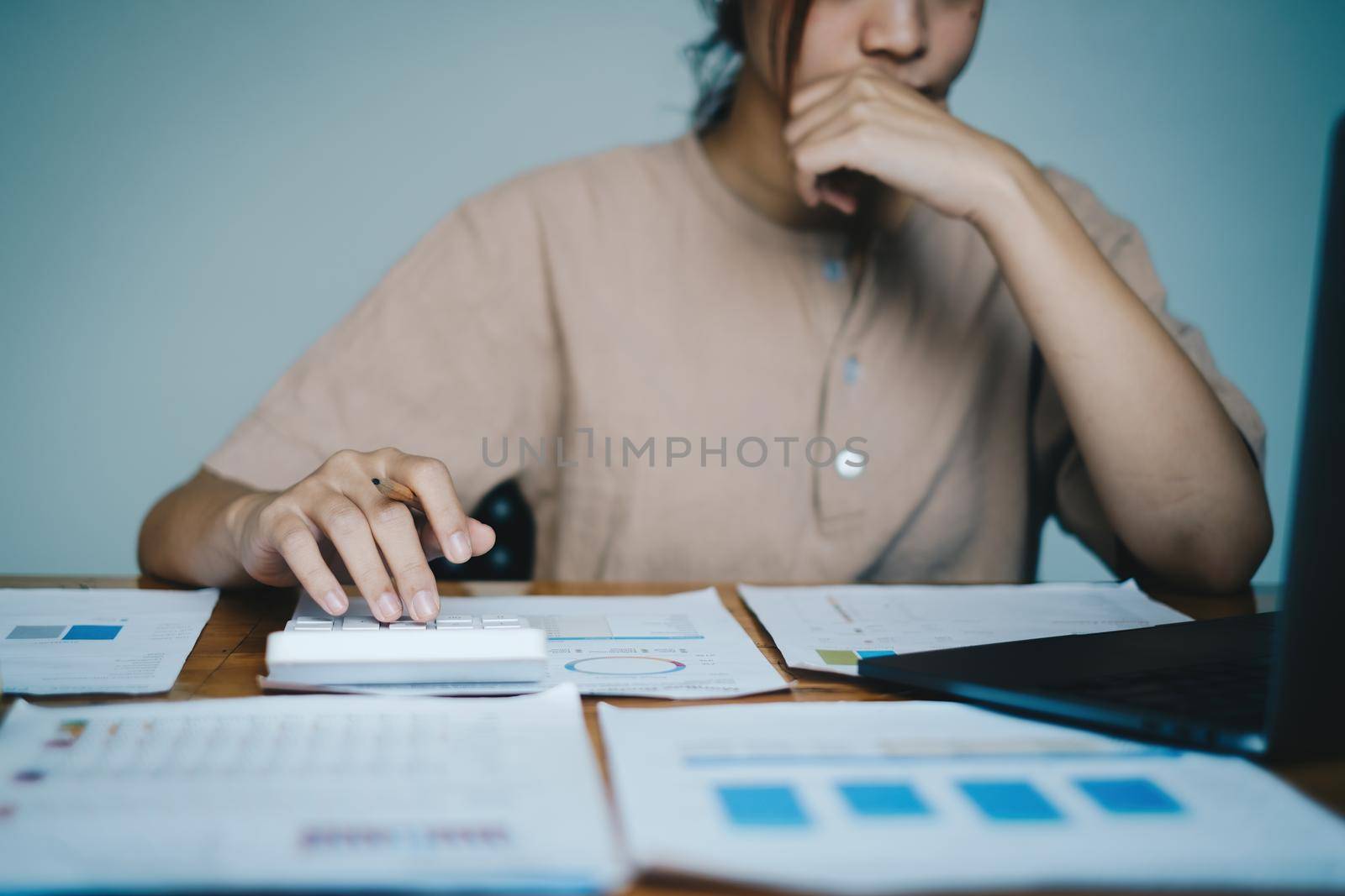 Asian Business woman or Accountant using calculator for audit finance budget on wooden desk in office, tax, accounting, statistics and analytic research concept