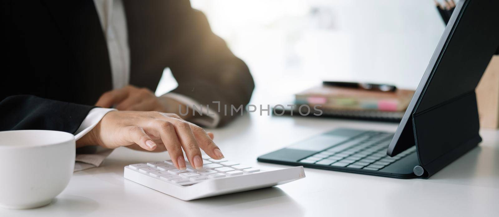 Close up woman planning budget, using calculator and digital tablet, reading documents, young female checking finances, counting bills or taxes, online banking services, sitting at desk.