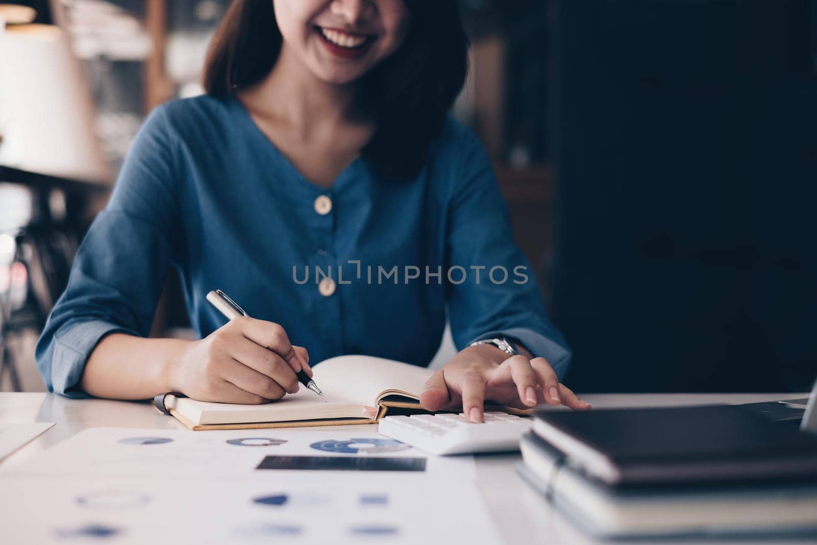 Asian Business Woman or Accountant hands holding pen writing in notebook with paperwork, account, audit and saving concept