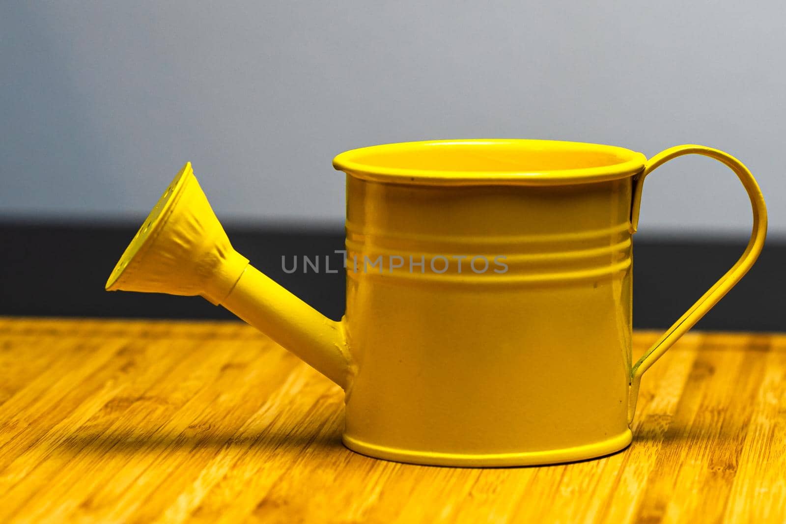 Yellow watering can on wooden table