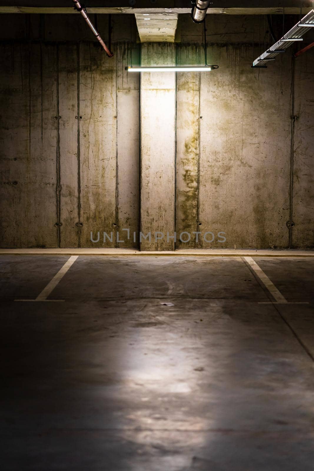 Empty parking lot with overhead dim light, underground parking garage.