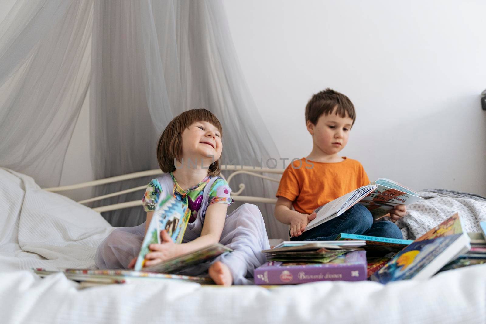 Two siblings reading books on the sofa by Varaksina