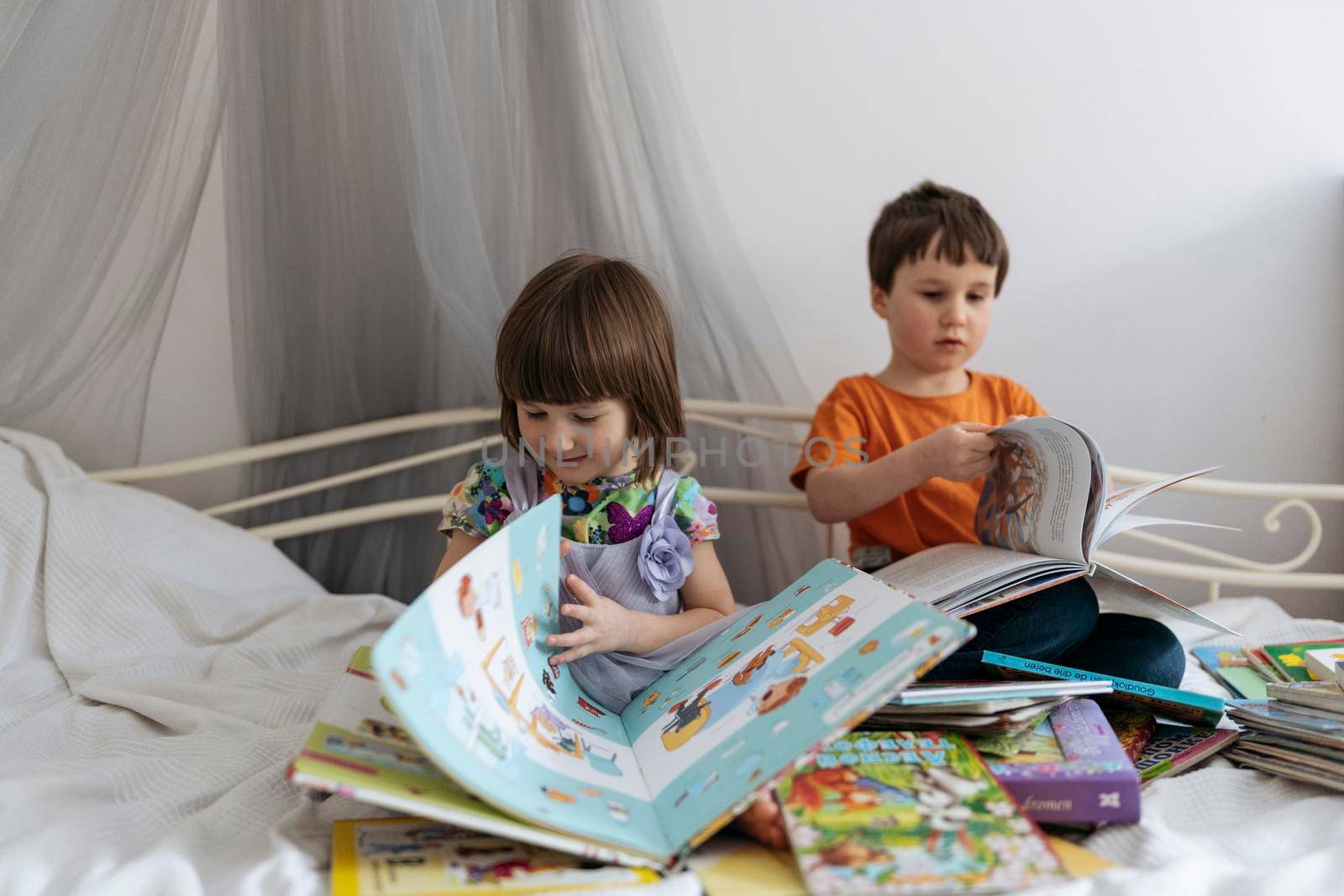 Two siblings reading books on the sofa by Varaksina