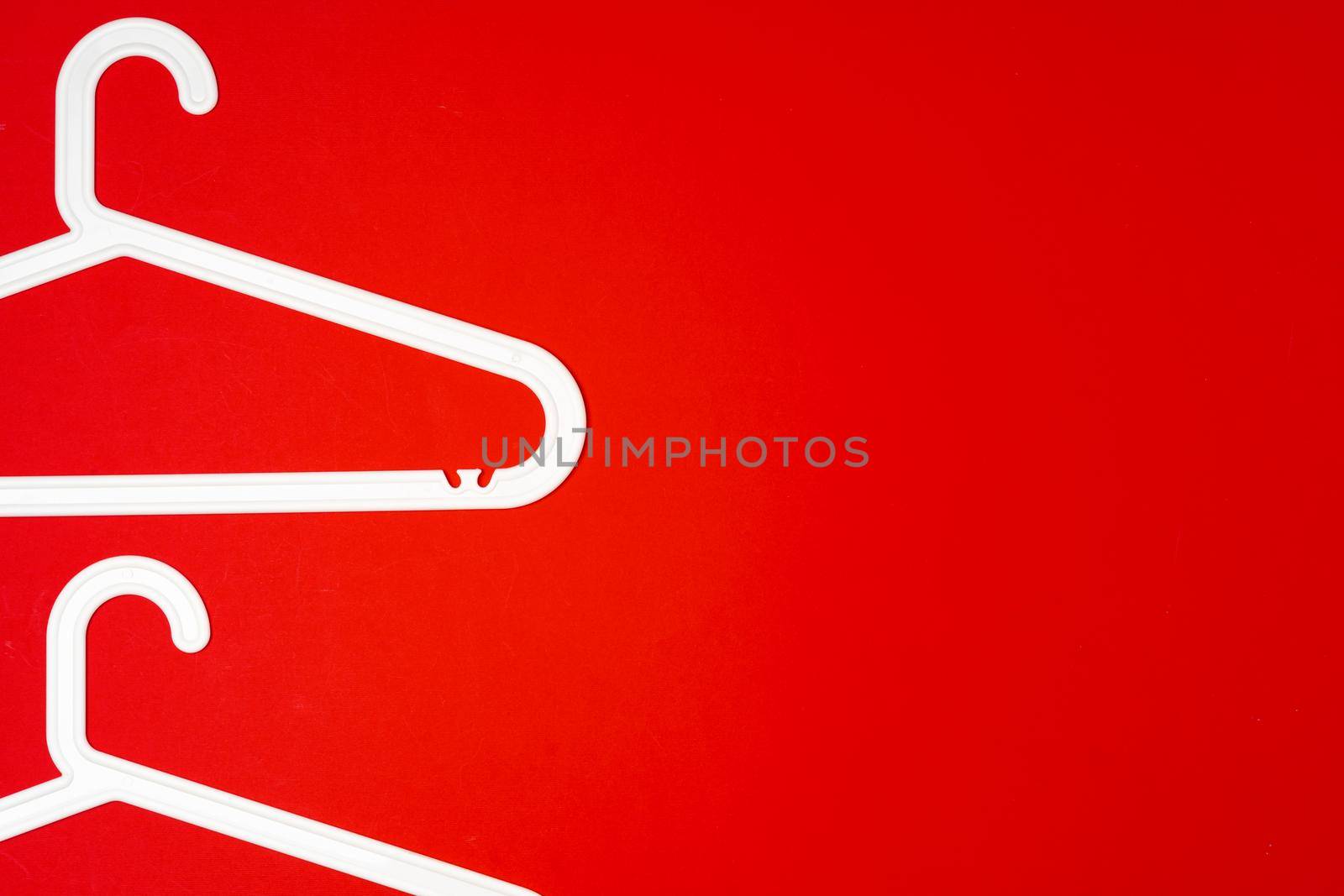 Hanger on red paper background. Minimalistic fashion concept. Top view by Fabrikasimf