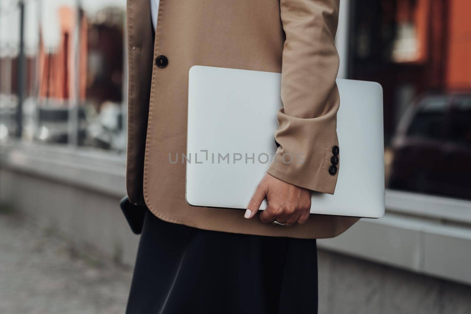 CloseUp Business Woman in a Brown Jacket Holding Laptop Outdoors by Romvy