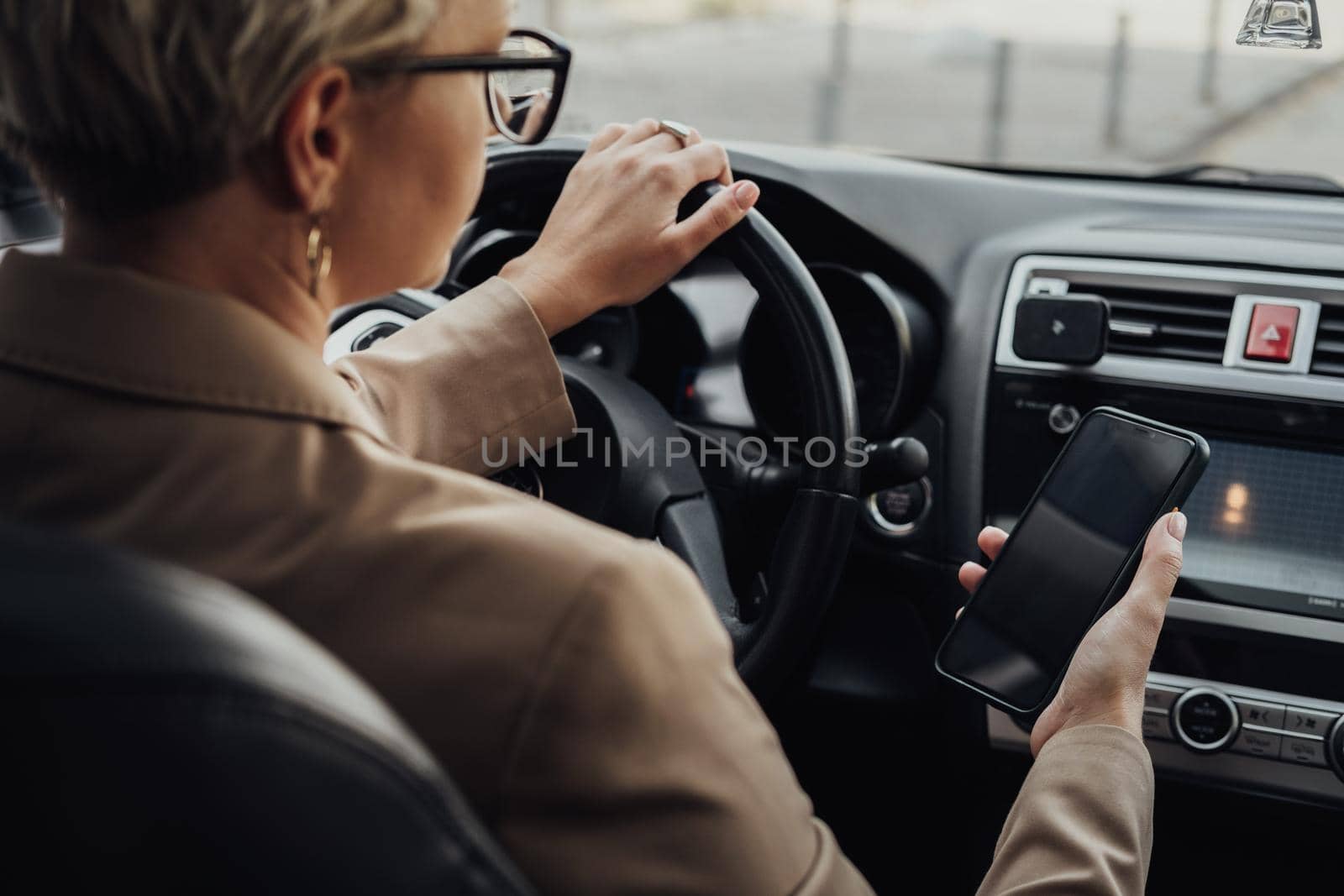 Business Woman Using Smartphone While Driving Car, View from Back Seat