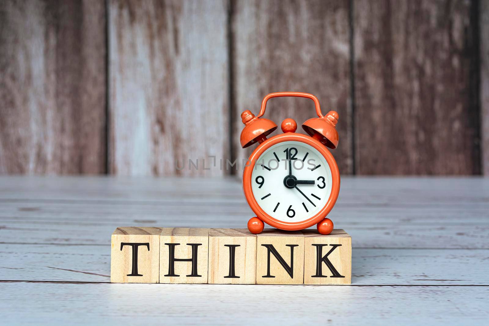 Think text on wooden blocks and alarm clock set at 3 o'clock on table. Business and idea concept.