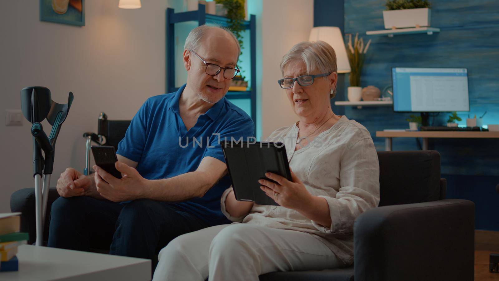 Grandparents using smartphone and digital tablet at home by DCStudio