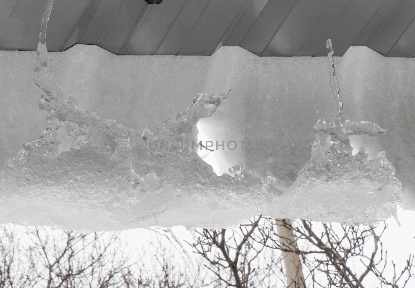 Icicles on the roof, white sky and iced water, winter by Taidundua