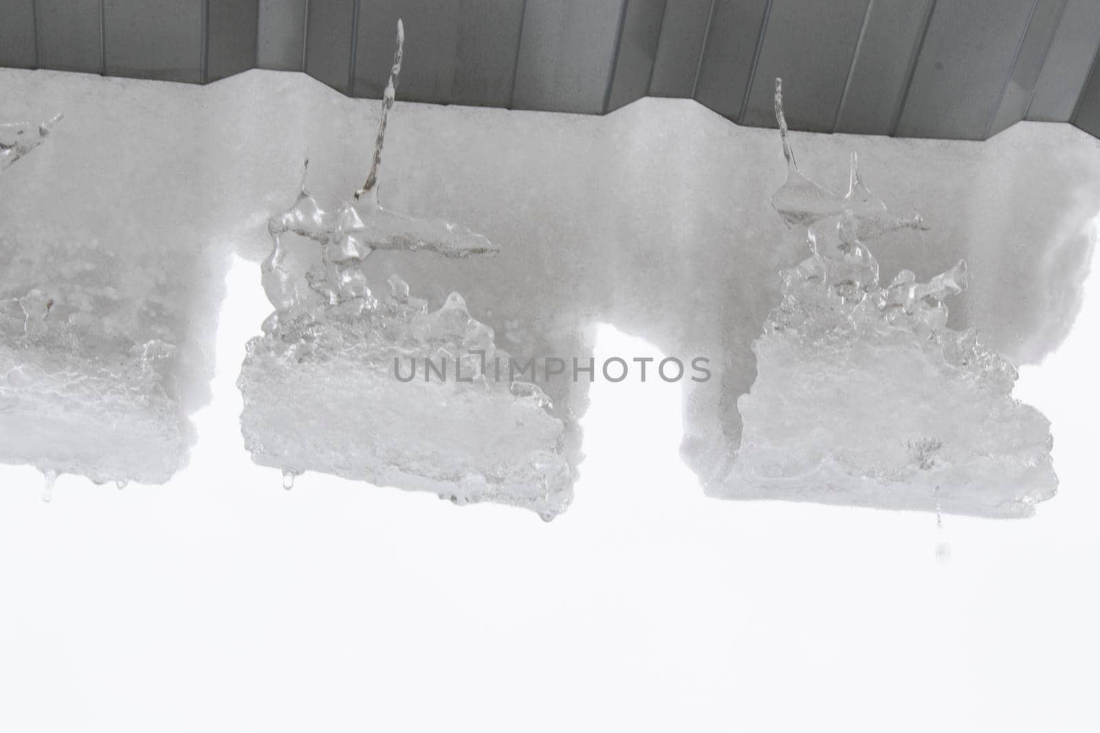 Icicles on the roof, white sky and iced water, winter by Taidundua