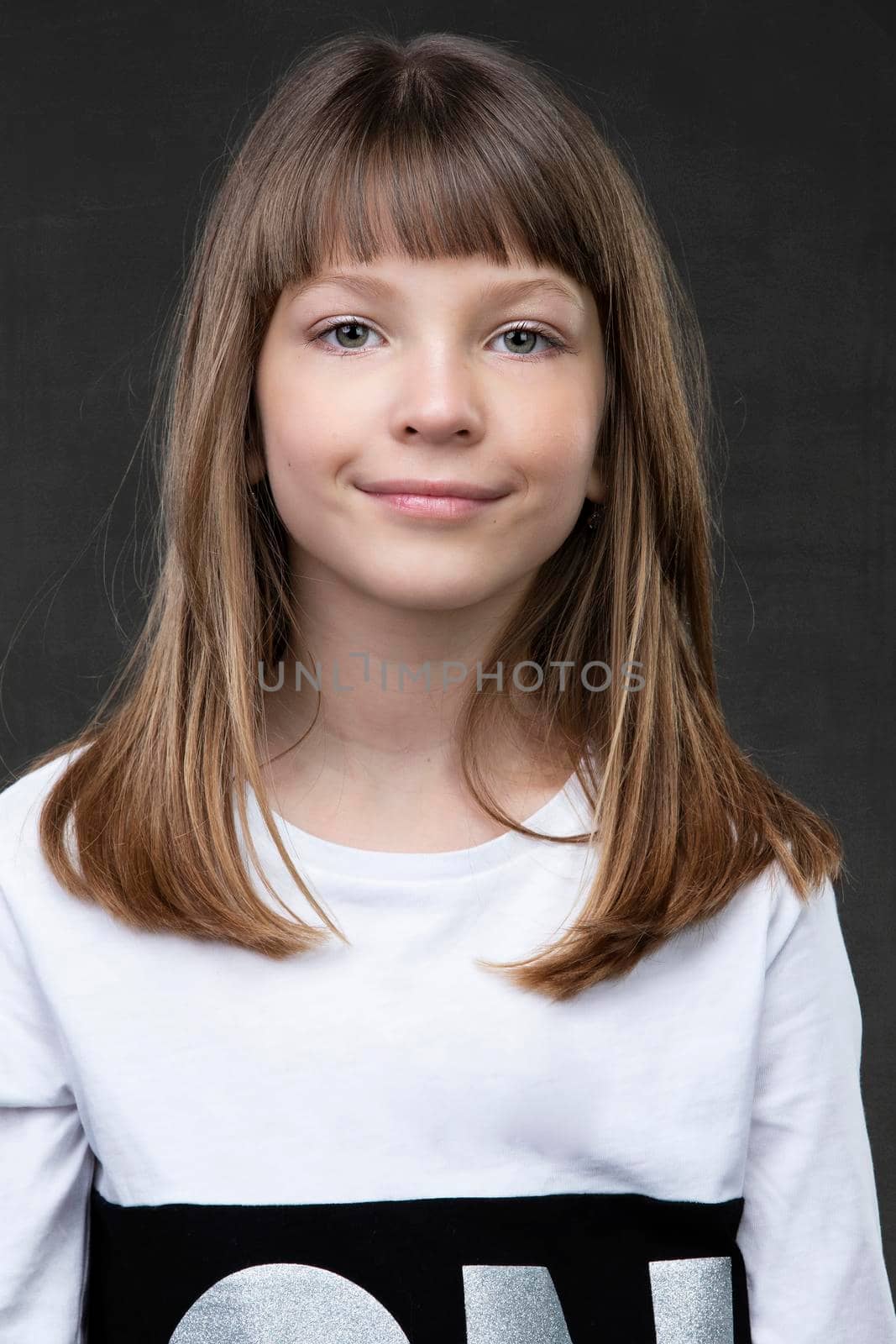A beautiful ten year old girl is looking at the camera and smiling.