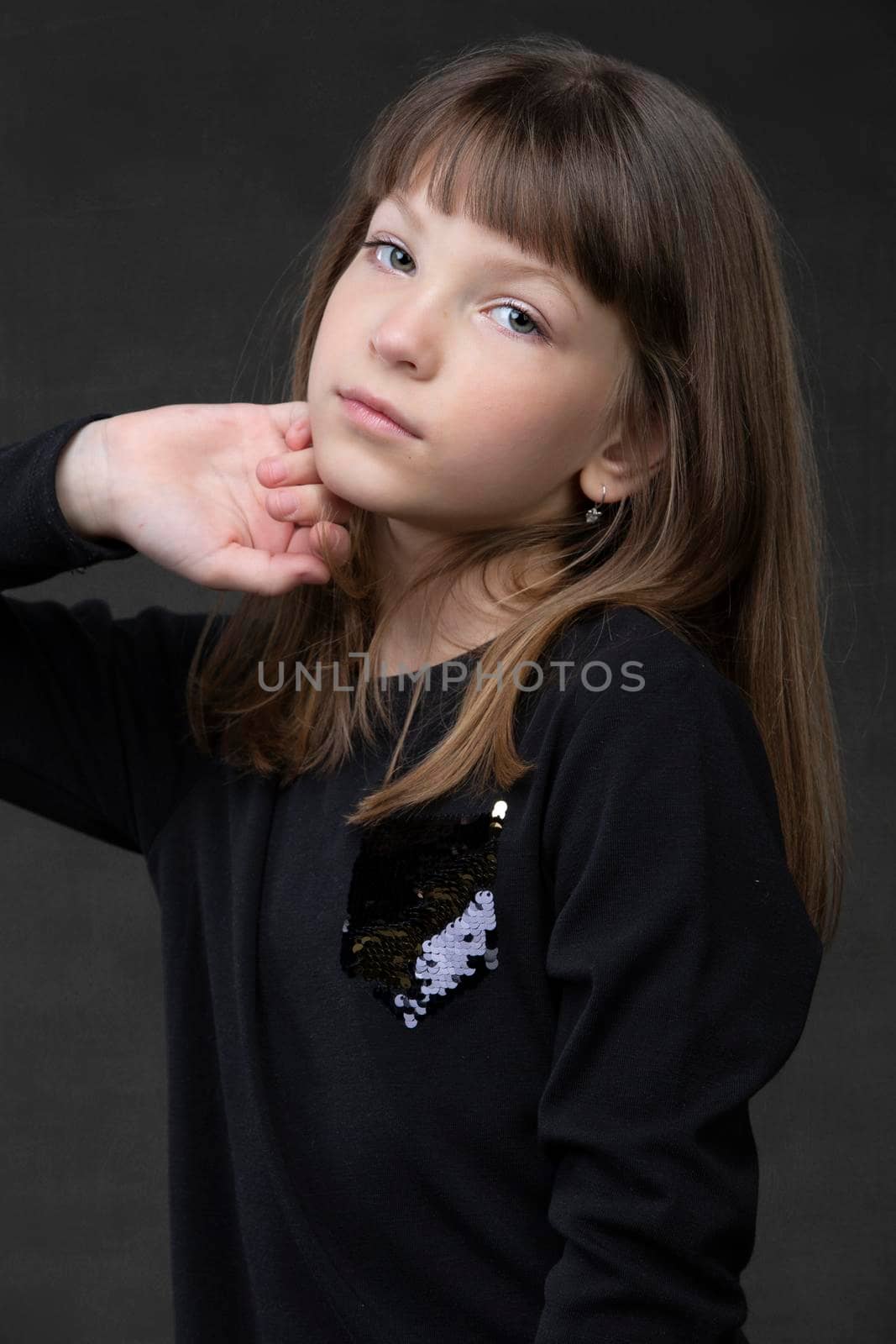 Beautiful little girl look at the camera on a gray background.