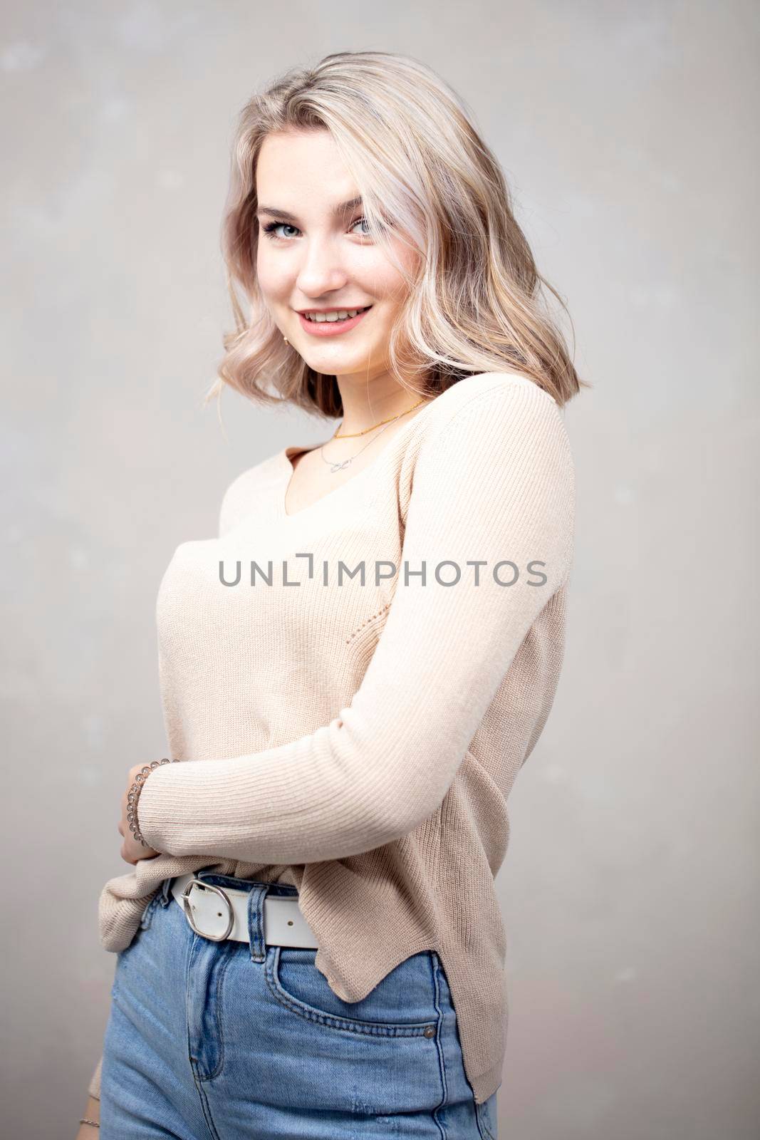 A beautiful young girl with blond hair and blue eyes looks at the camera and smiles. The girl is seventeen years old.